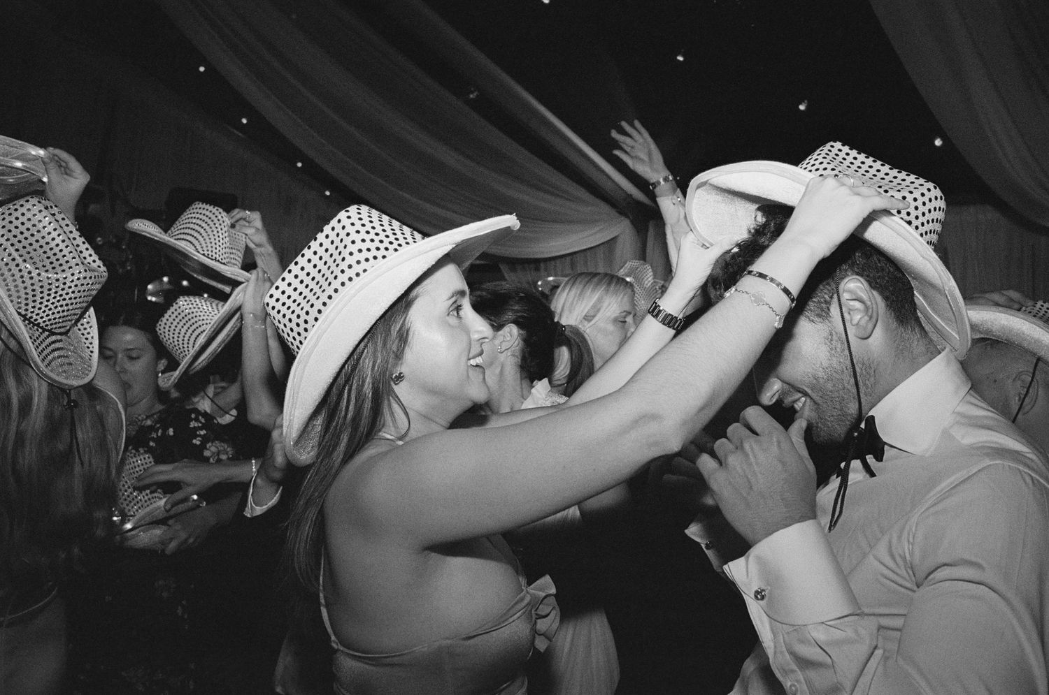 Wedding reception guests dancing and celebrating on a crowded dance floor.