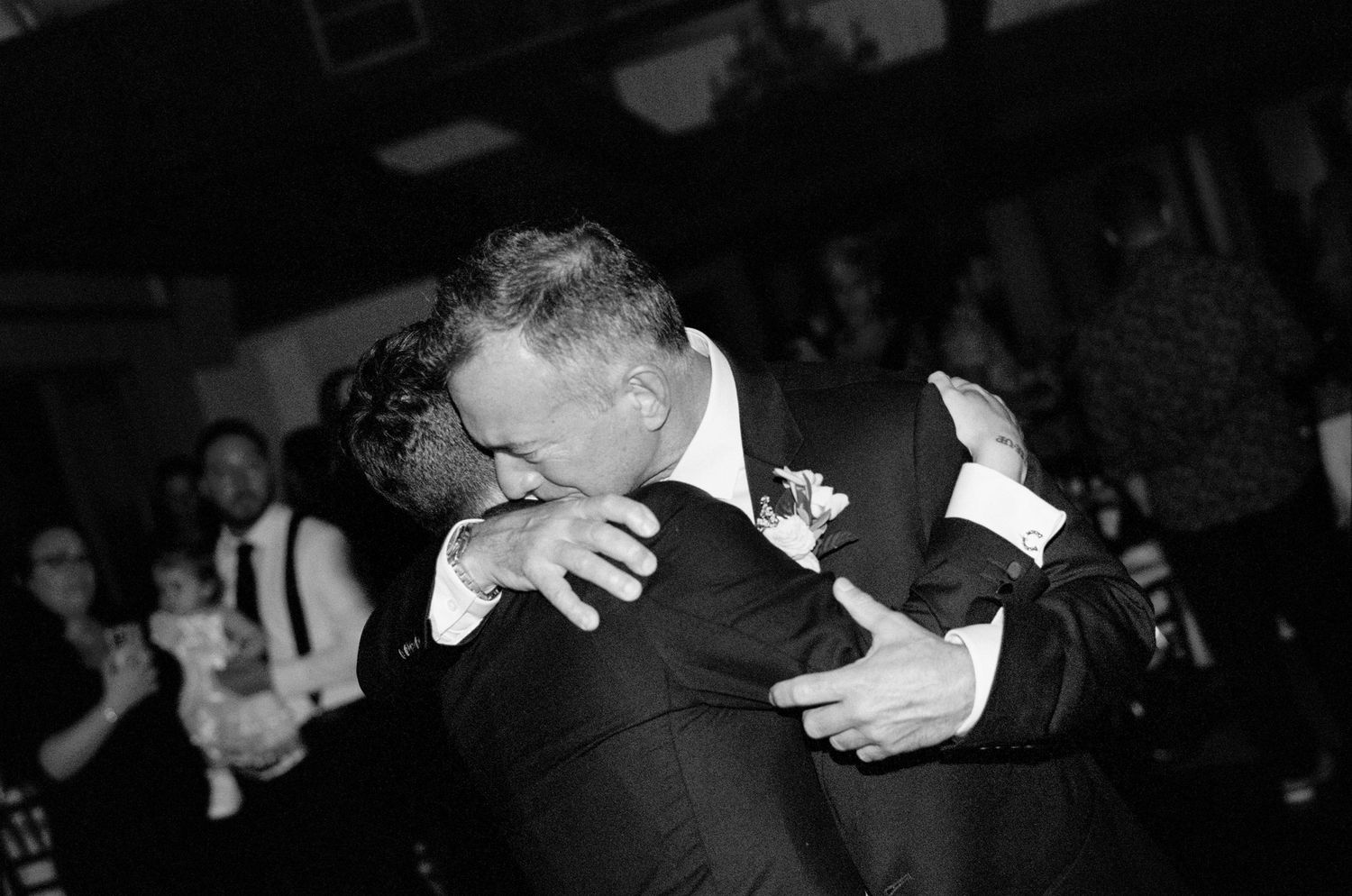 Wedding guests dance together in formal attire at an evening reception celebration.