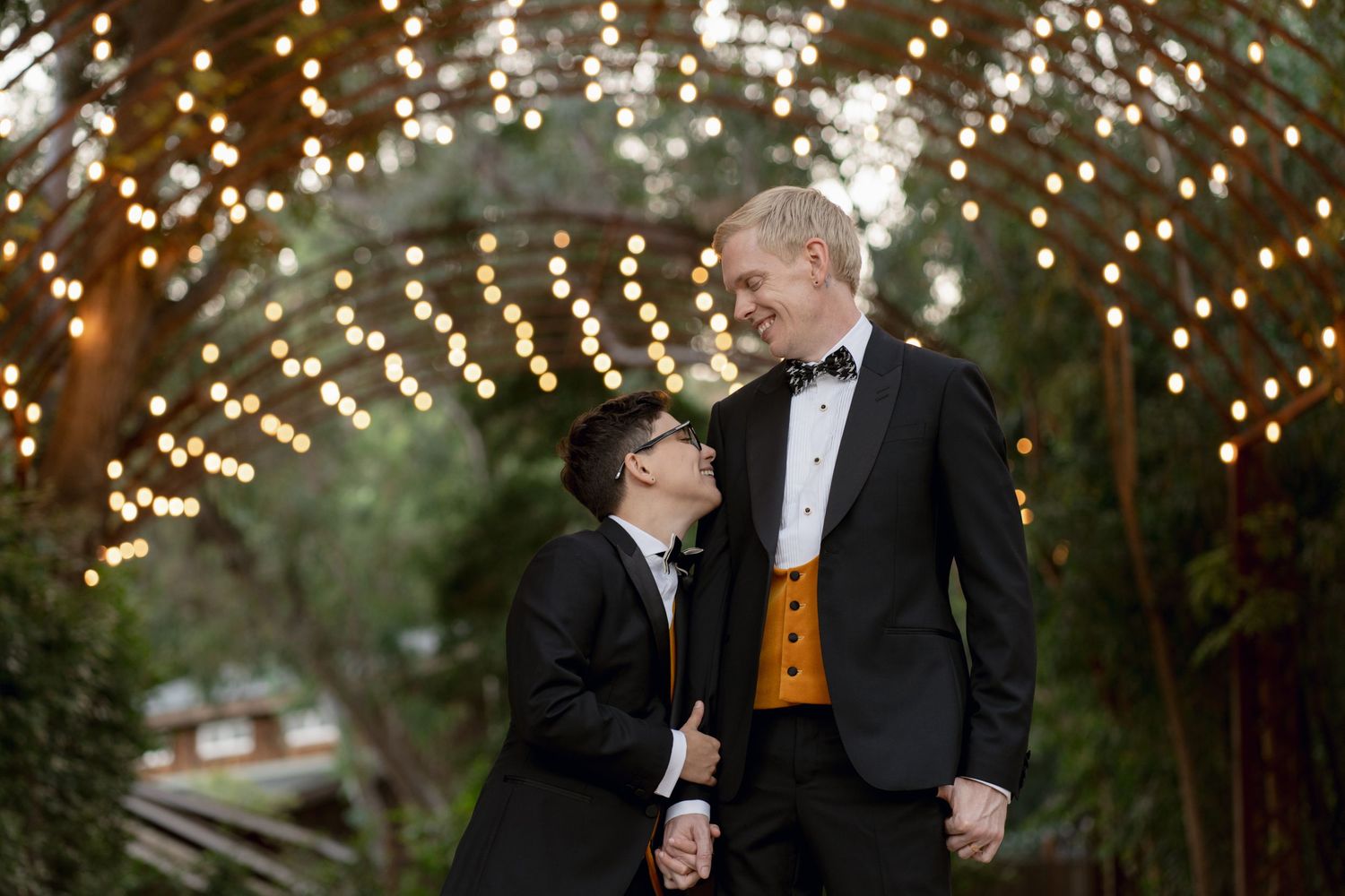 A couple sharing an intimate moment under twinkling lights at dusk.