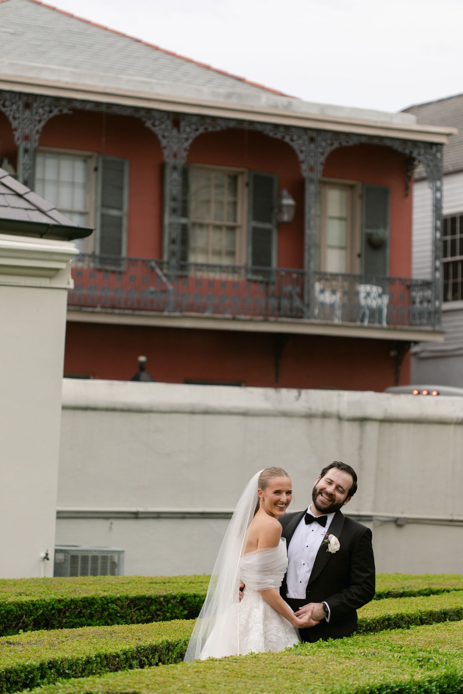Newlyweds pose for portrait in front of historic building with ornate architecture.