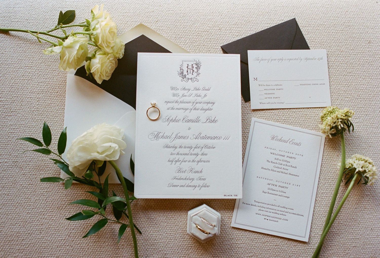 Elegant wedding invitation suite with white roses and greenery on light gray background.