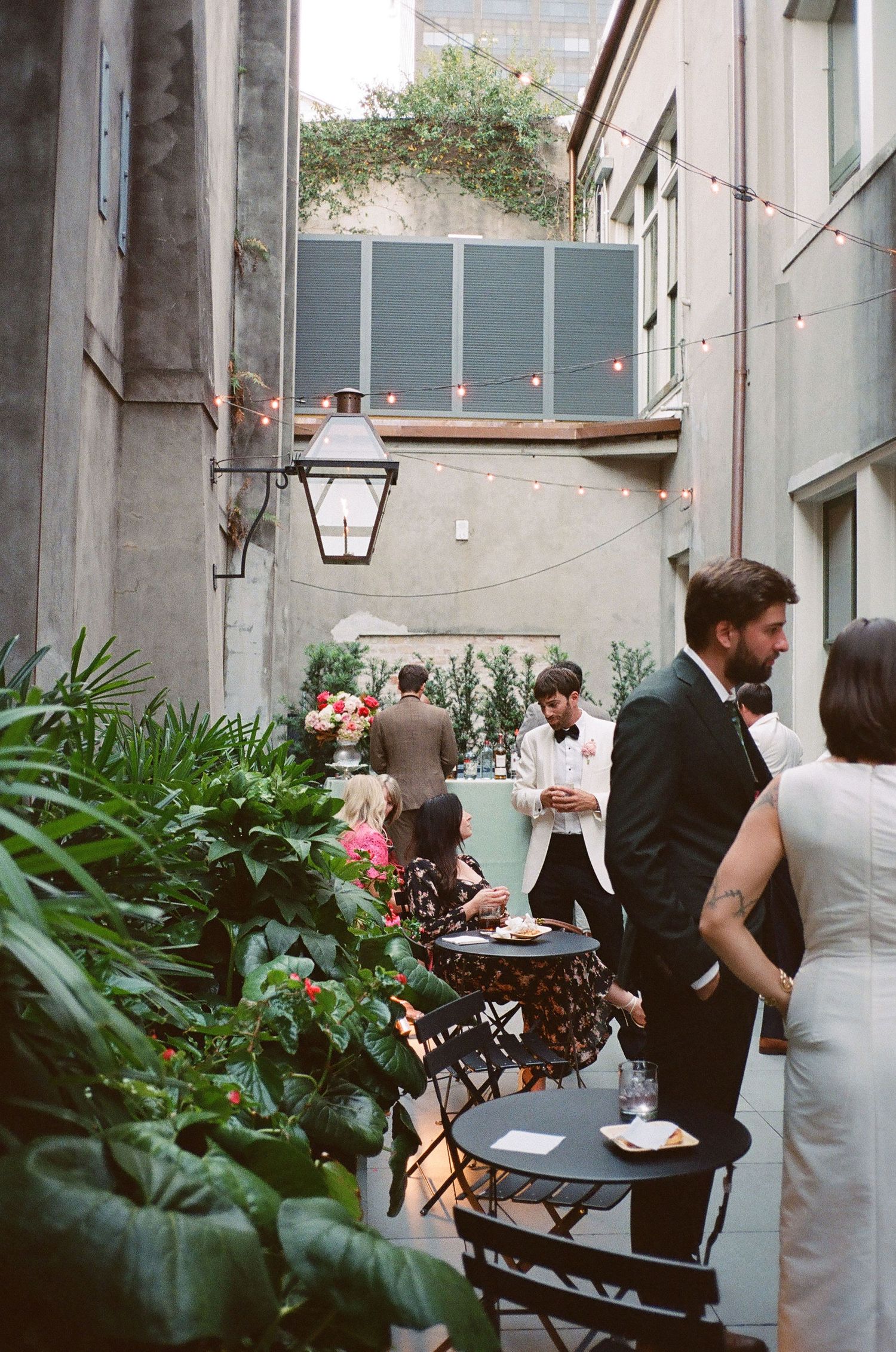 Intimate courtyard gathering with string lights, plants and bistro tables.