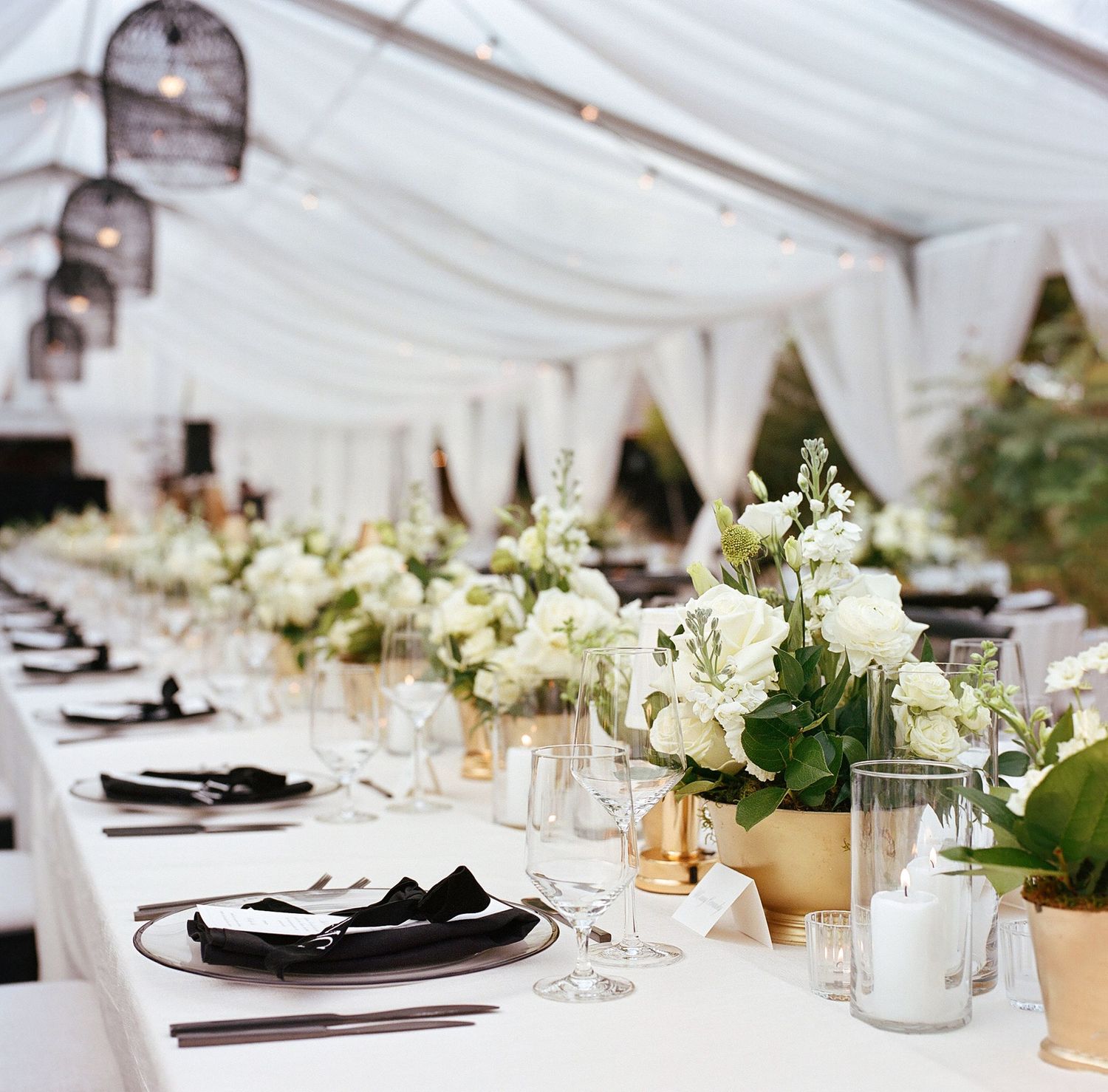 White wedding reception tables with elegant floral centerpieces and formal place settings.