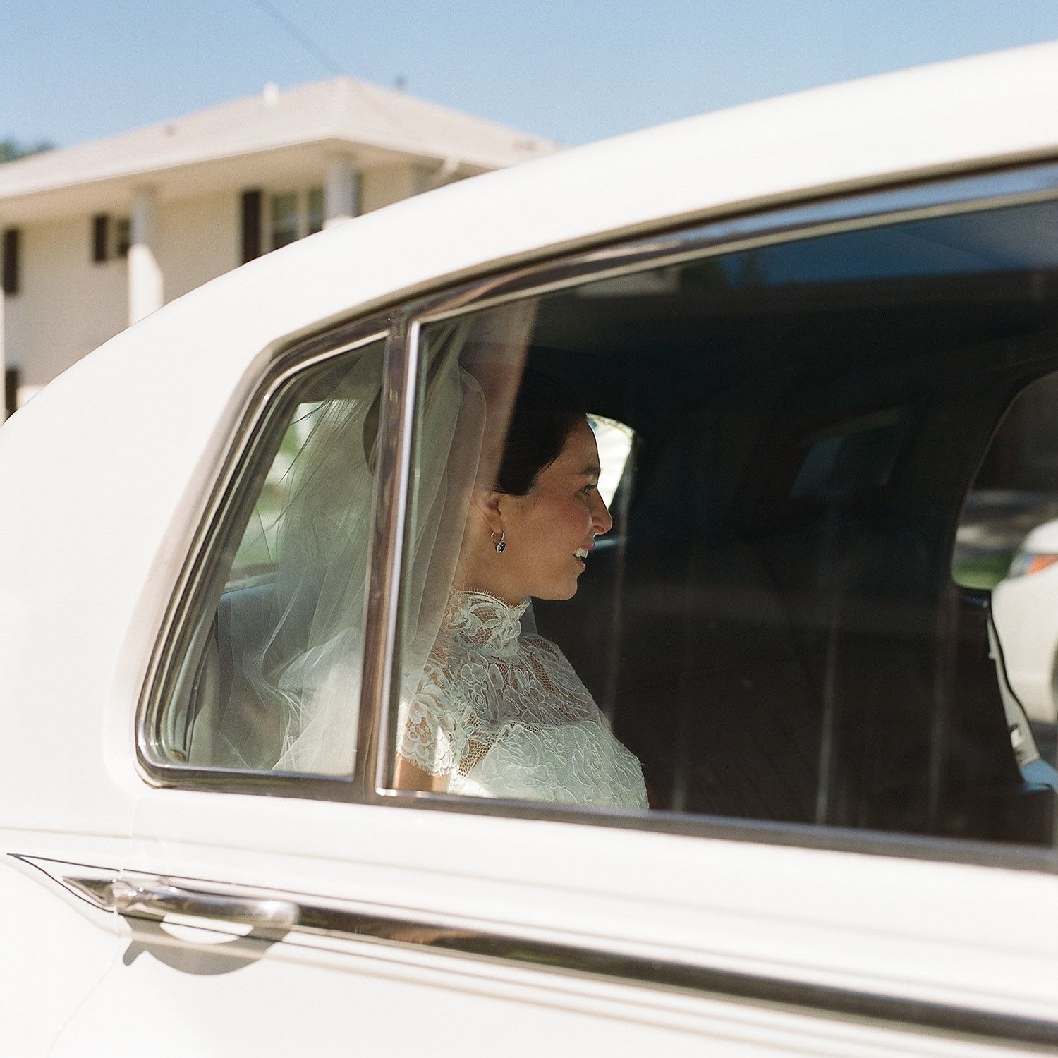 Classic white wedding car with passengers visible through the window.