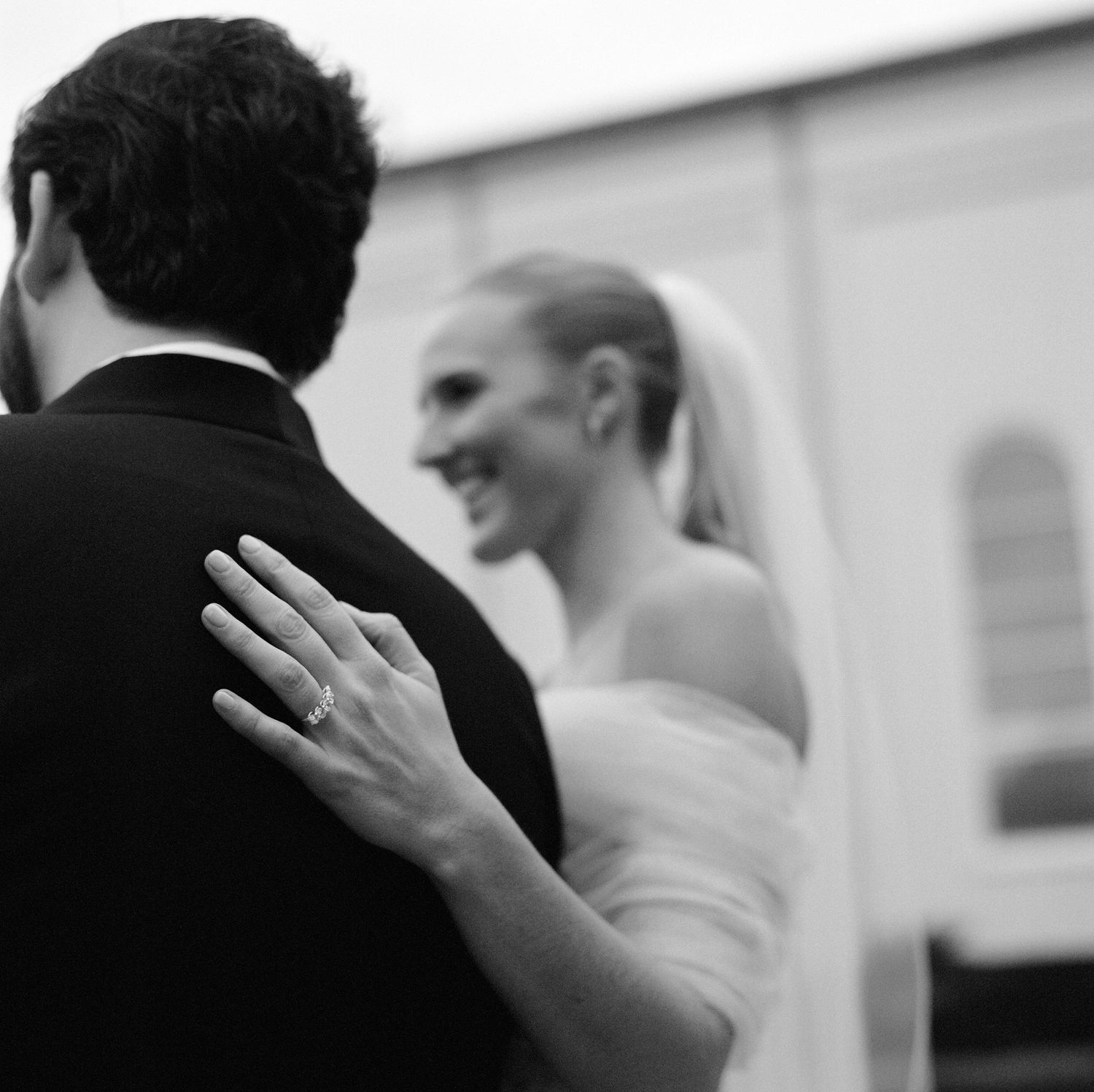 Black and white artistic shot capturing gestures and movement during a wedding celebration.