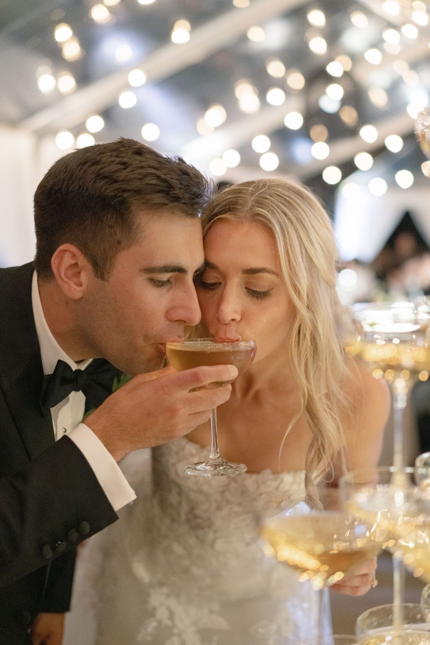 Elegant wedding reception scene with champagne glasses and twinkling lights in the background.