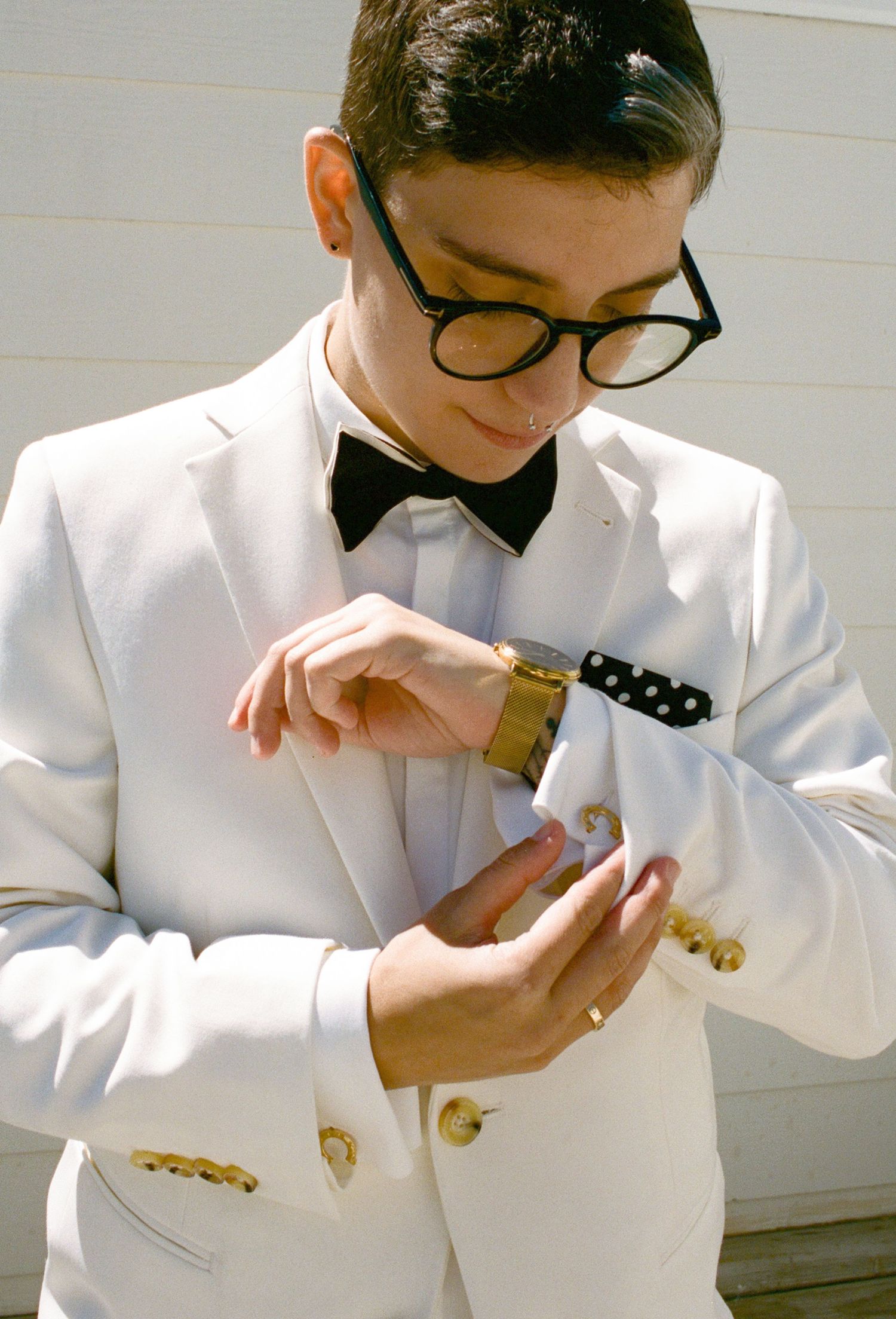 Person in white formal attire adjusting their bowtie in sequential shots.