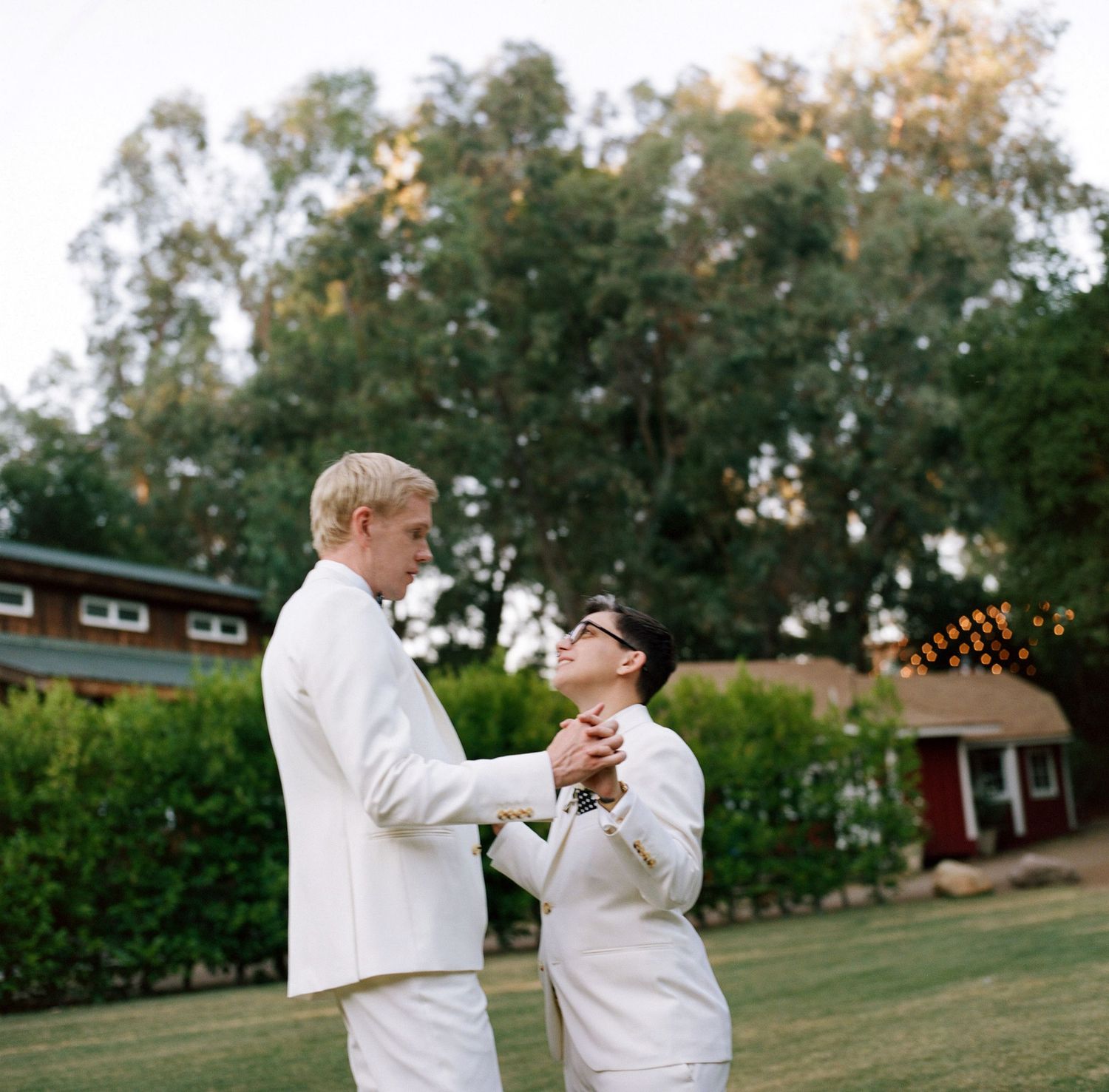 Two people dancing together on a grassy lawn at sunset.