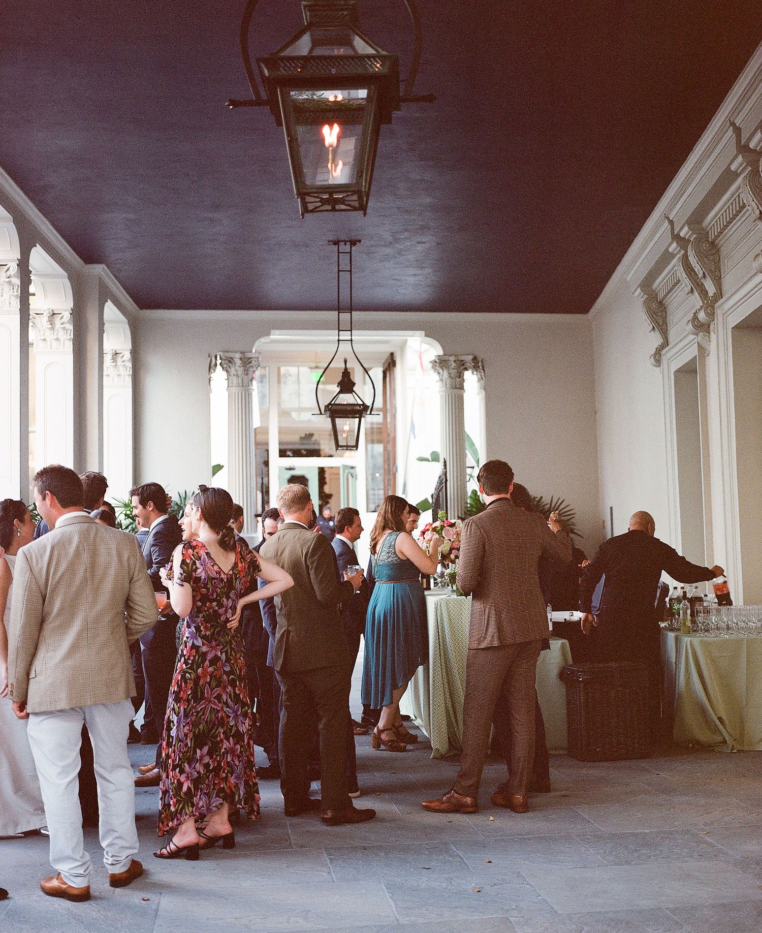 Wedding reception guests socializing in an elegant hall with hanging lanterns.
