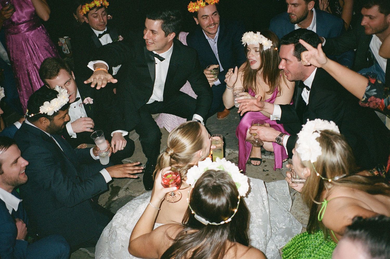 Wedding reception dance floor filled with guests celebrating under dim lighting.
