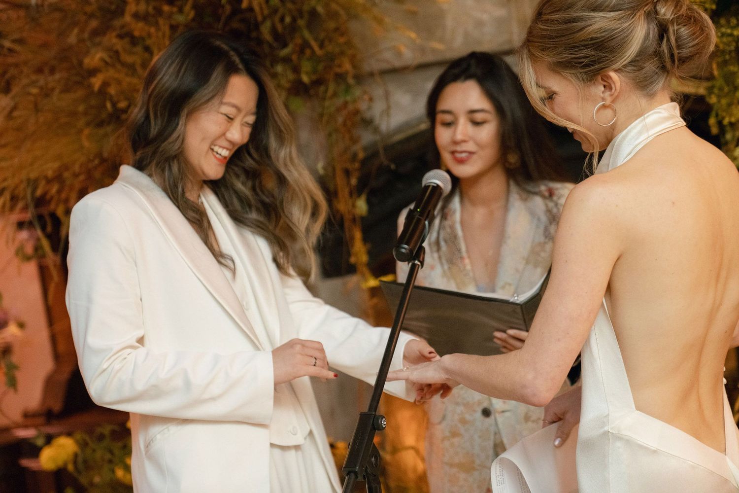 Guests in white attire celebrating at an intimate wedding reception with autumn-themed decorations.