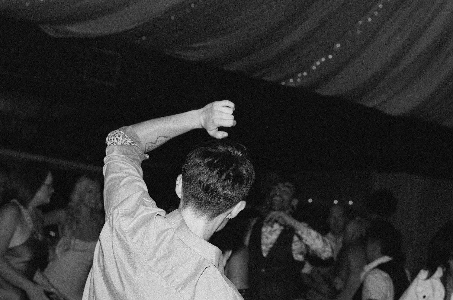 Silhouettes of people dancing at a dimly lit wedding reception.