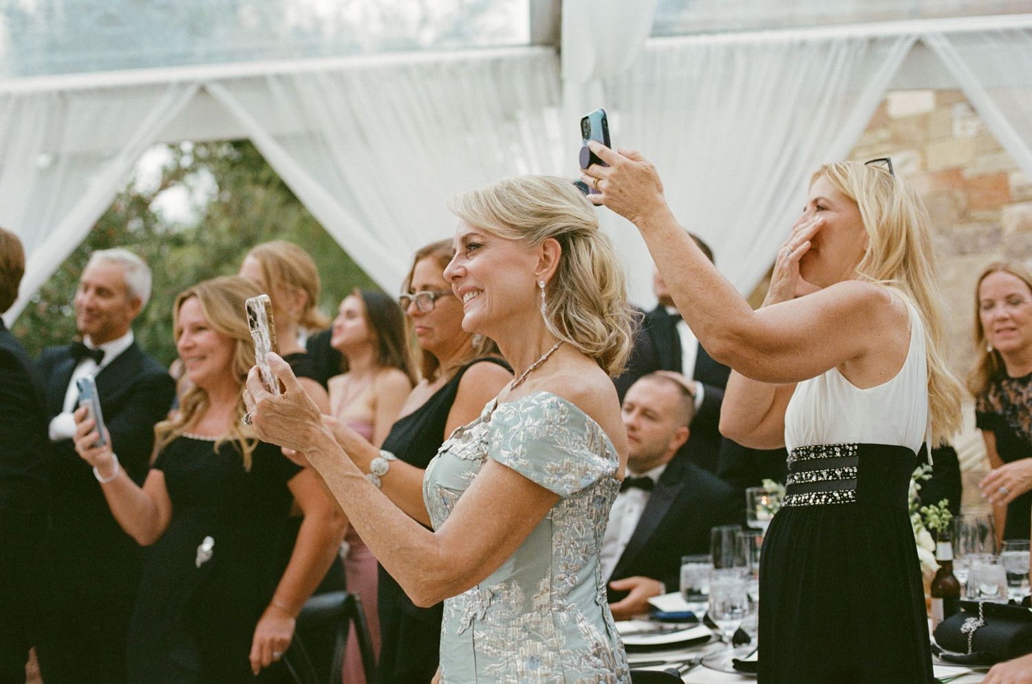 Wedding guests taking photos with phones during celebration event.