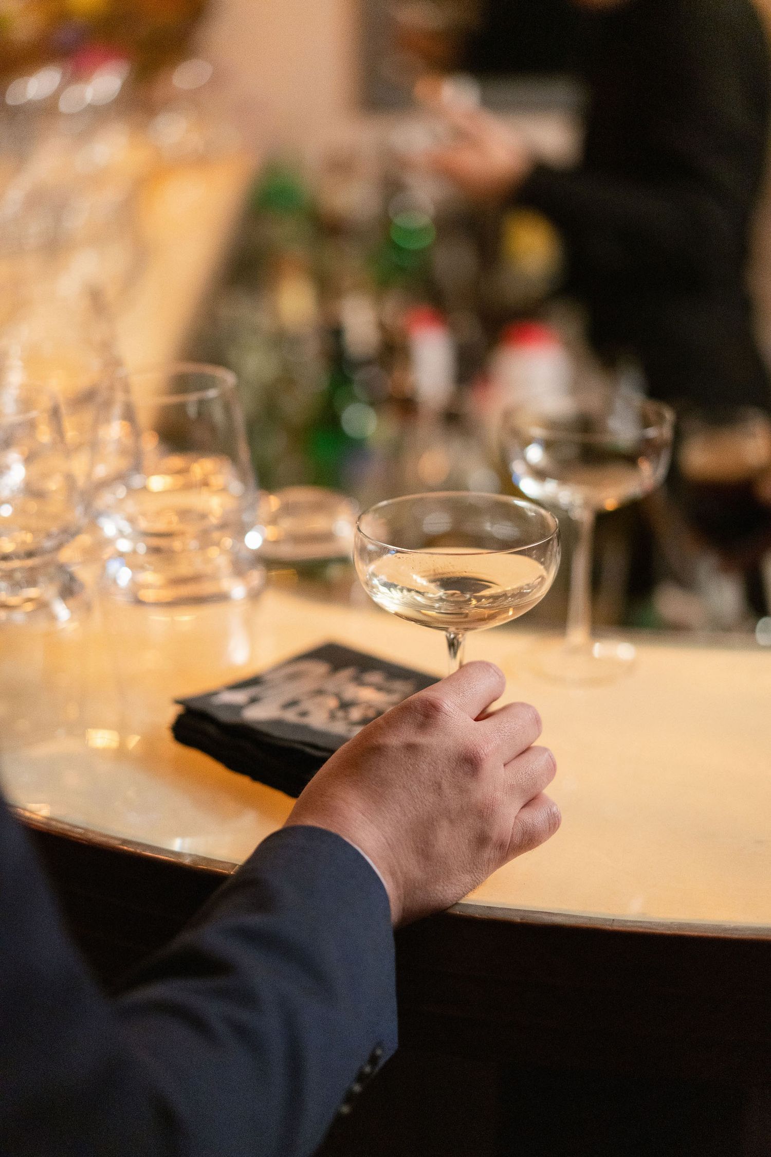 Close-up of hands and wine glasses on a formal dining table.