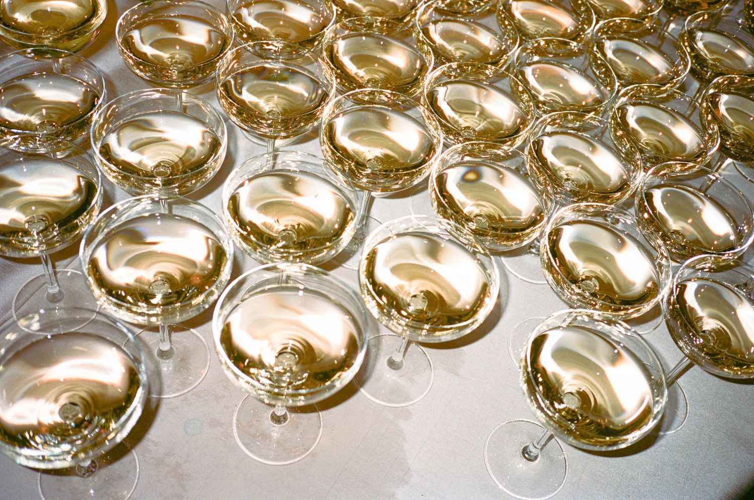 Multiple champagne glasses arranged in rows creating a golden pattern.