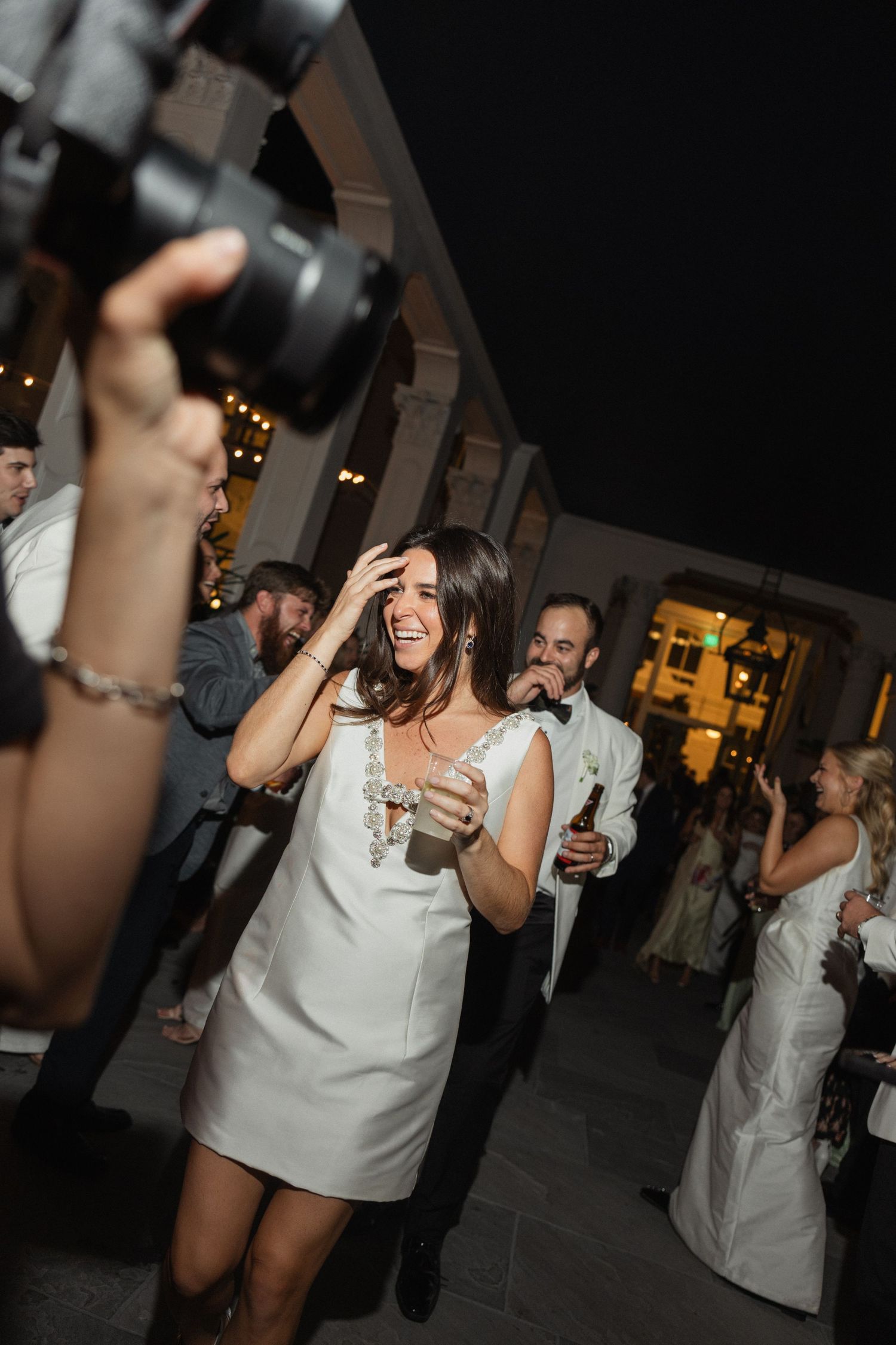 Wedding reception guests dancing and celebrating in evening outdoor setting.