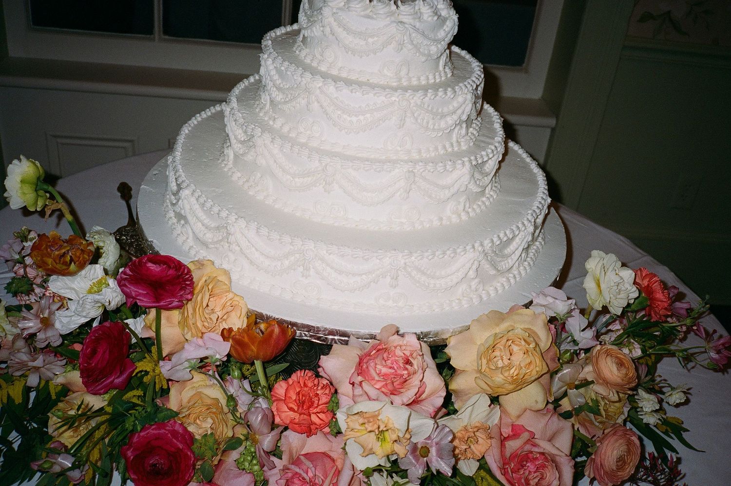 Elegant white wedding cake decorated with fresh coral and peach roses.