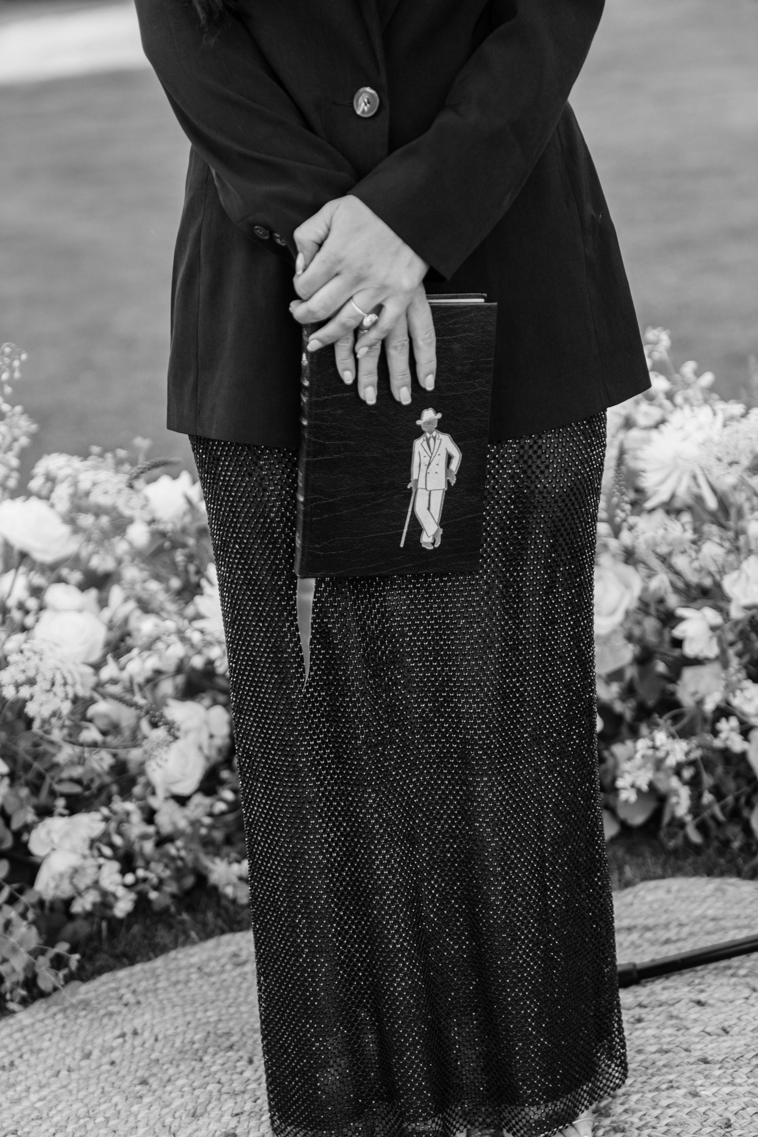 Detail shot of formal black attire and white floral decorations at an outdoor event.
