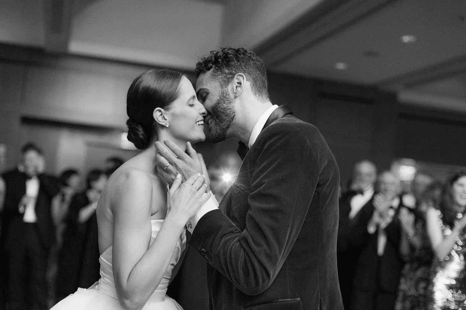 A romantic dance scene captured in black and white at an indoor wedding reception.