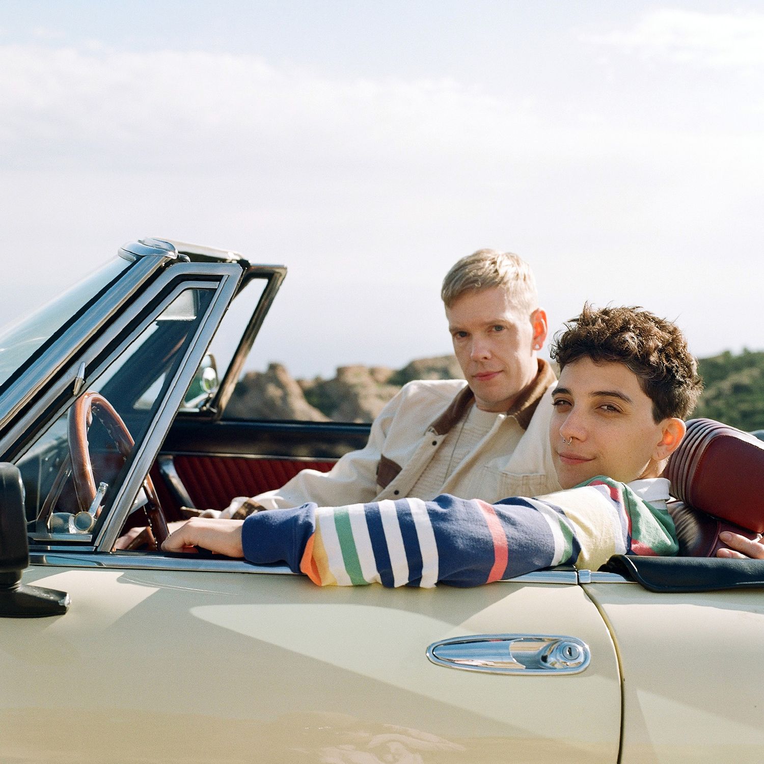 Friends relaxing in vintage convertible car on sunny day.