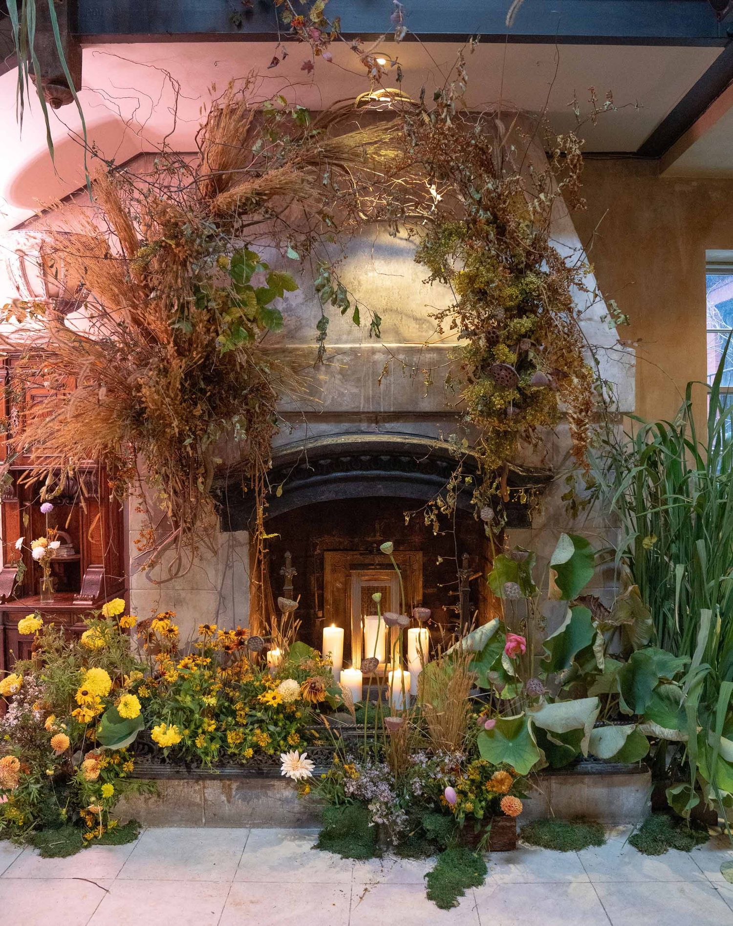 Garden-inspired floral installation with yellow flowers and greenery creates a natural archway indoors.