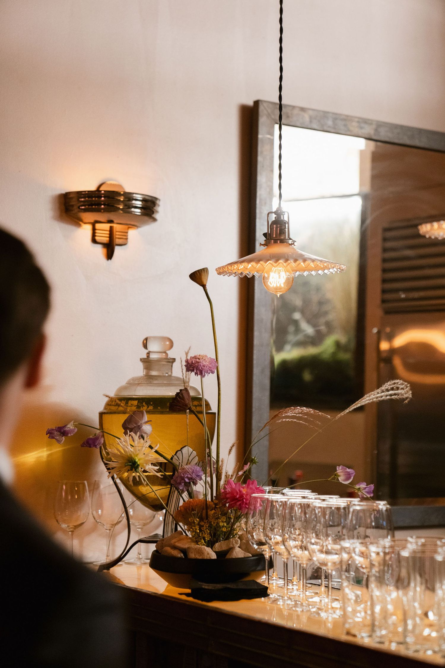 Wedding reception bar setup with vintage lighting and glassware arrangements.