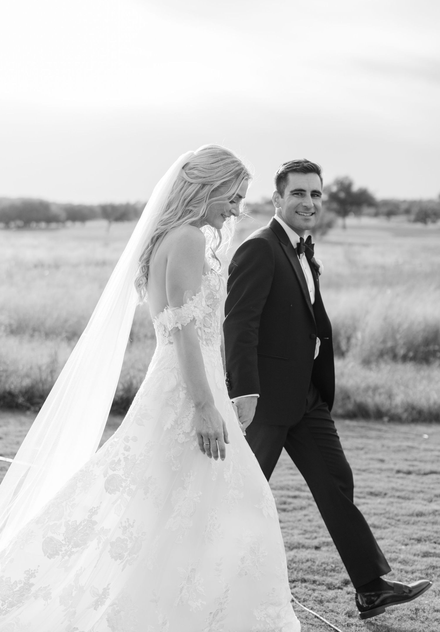 Wedding couple walking through a scenic field on their special day.