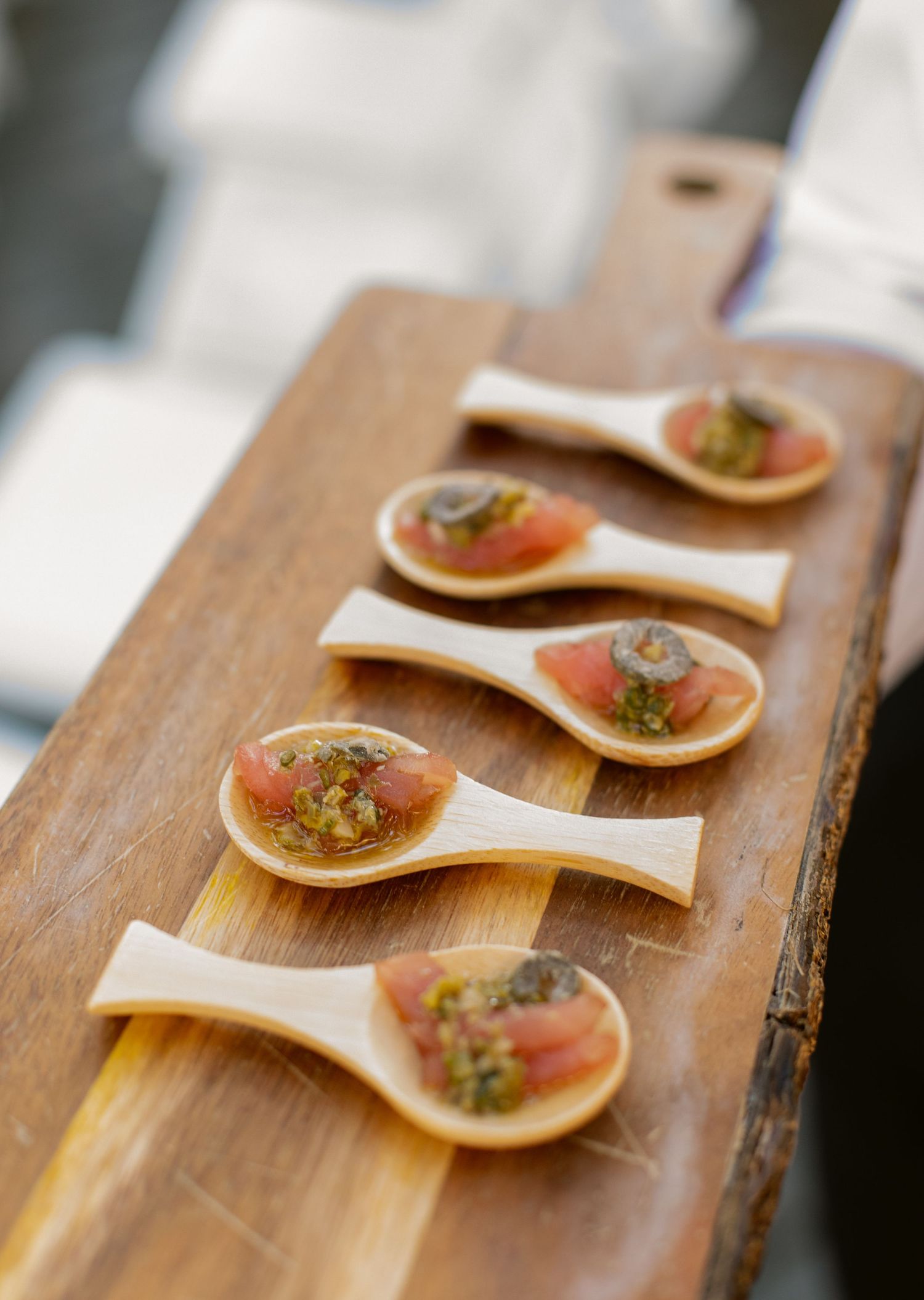 Elegant appetizers served on wooden spoons at an upscale event.