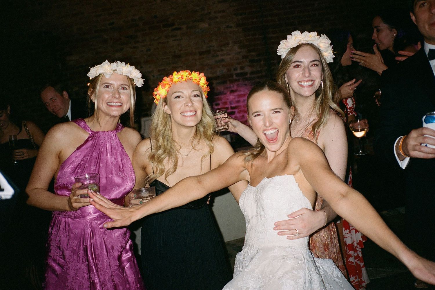Wedding reception dance floor filled with guests in formal attire and colorful dresses.