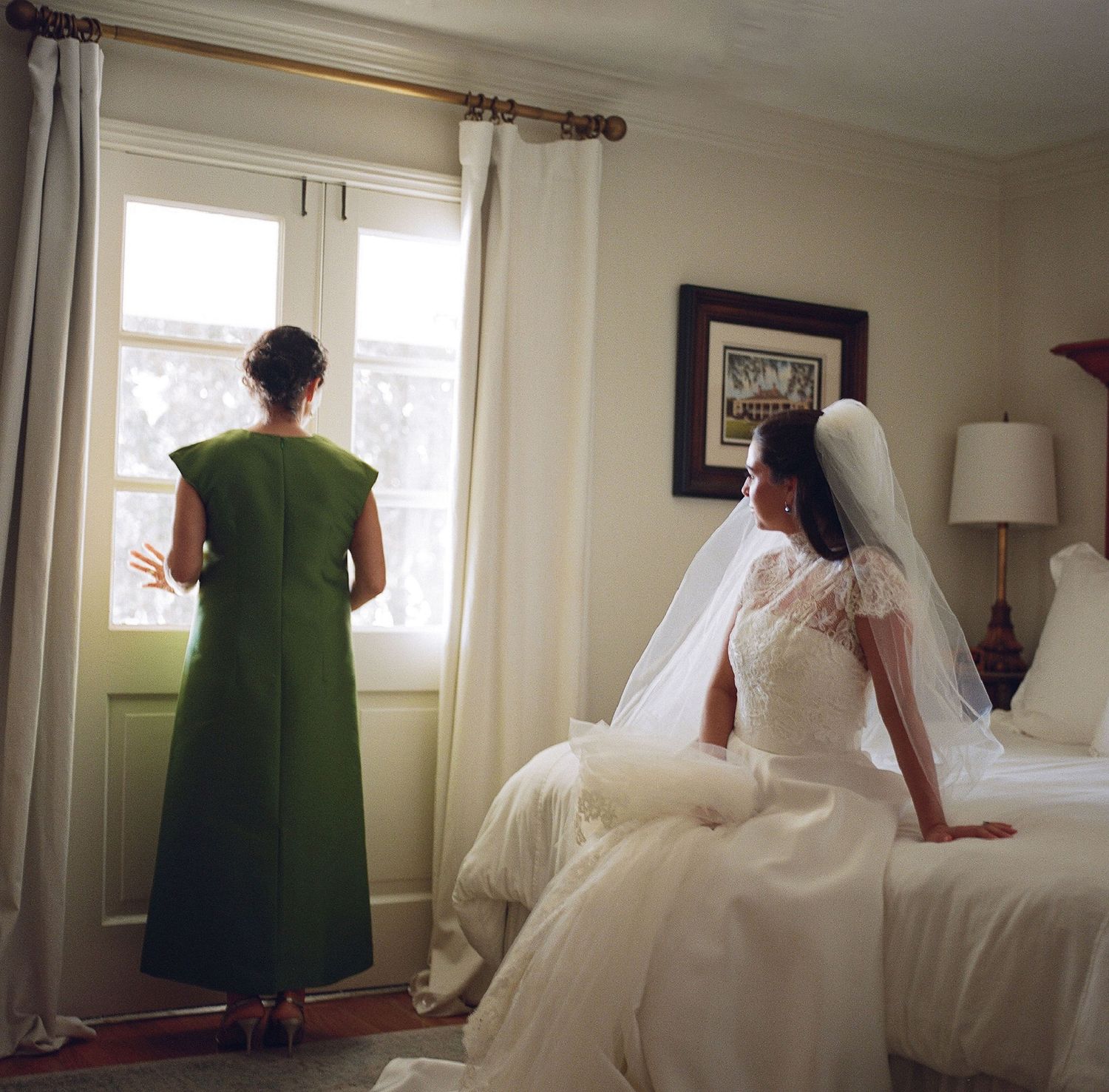 A wedding preparation scene with two people by a bright window in a bedroom.