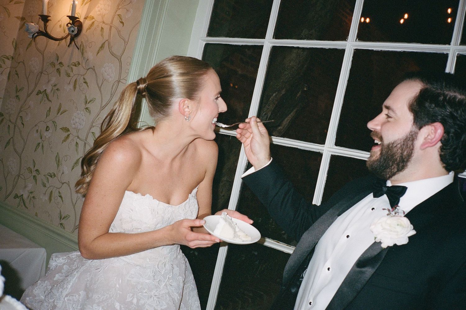 Wedding couple sharing cake during traditional cake cutting ceremony.
