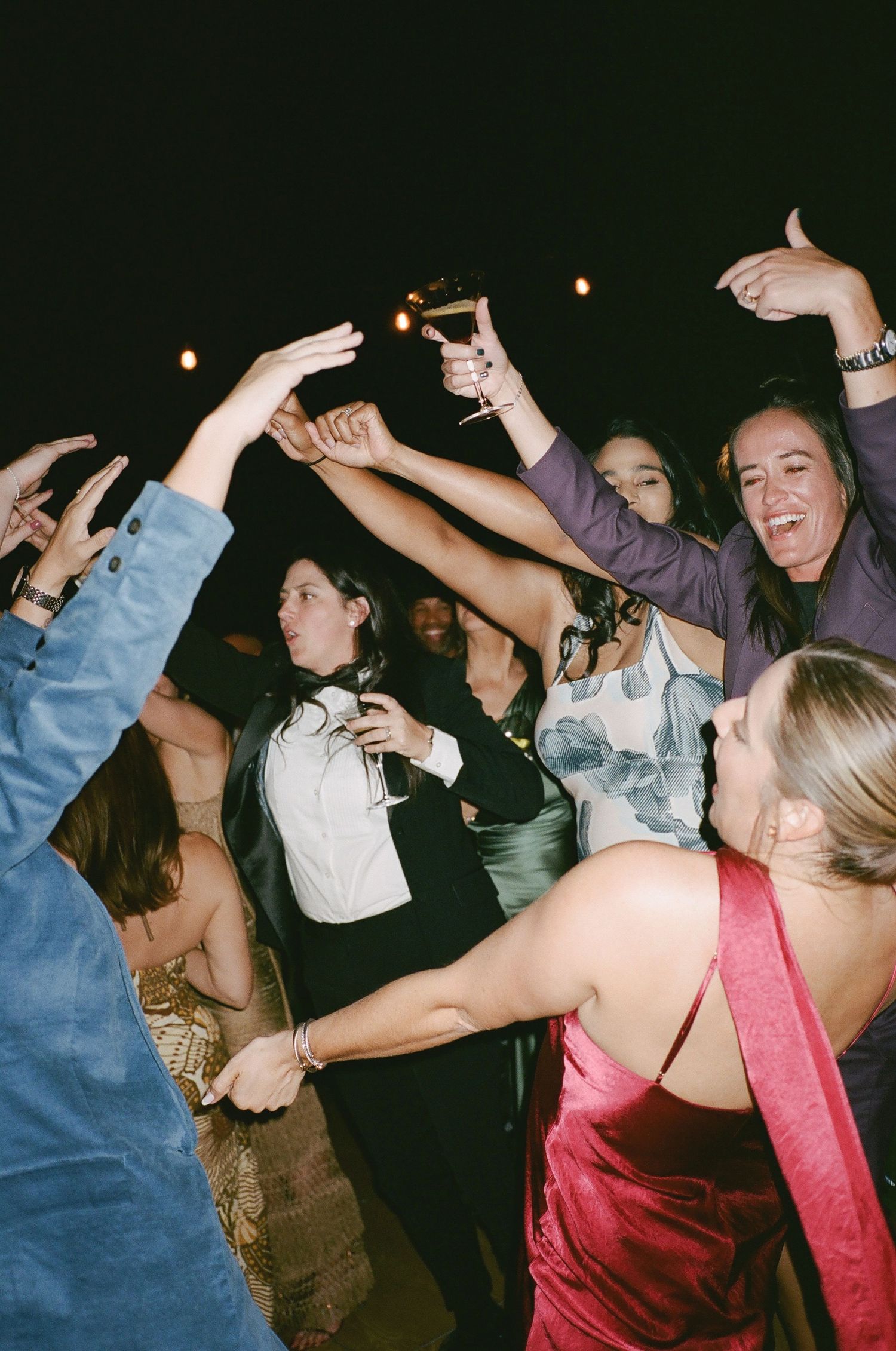 Crowd of people dancing with raised arms at a nighttime party.