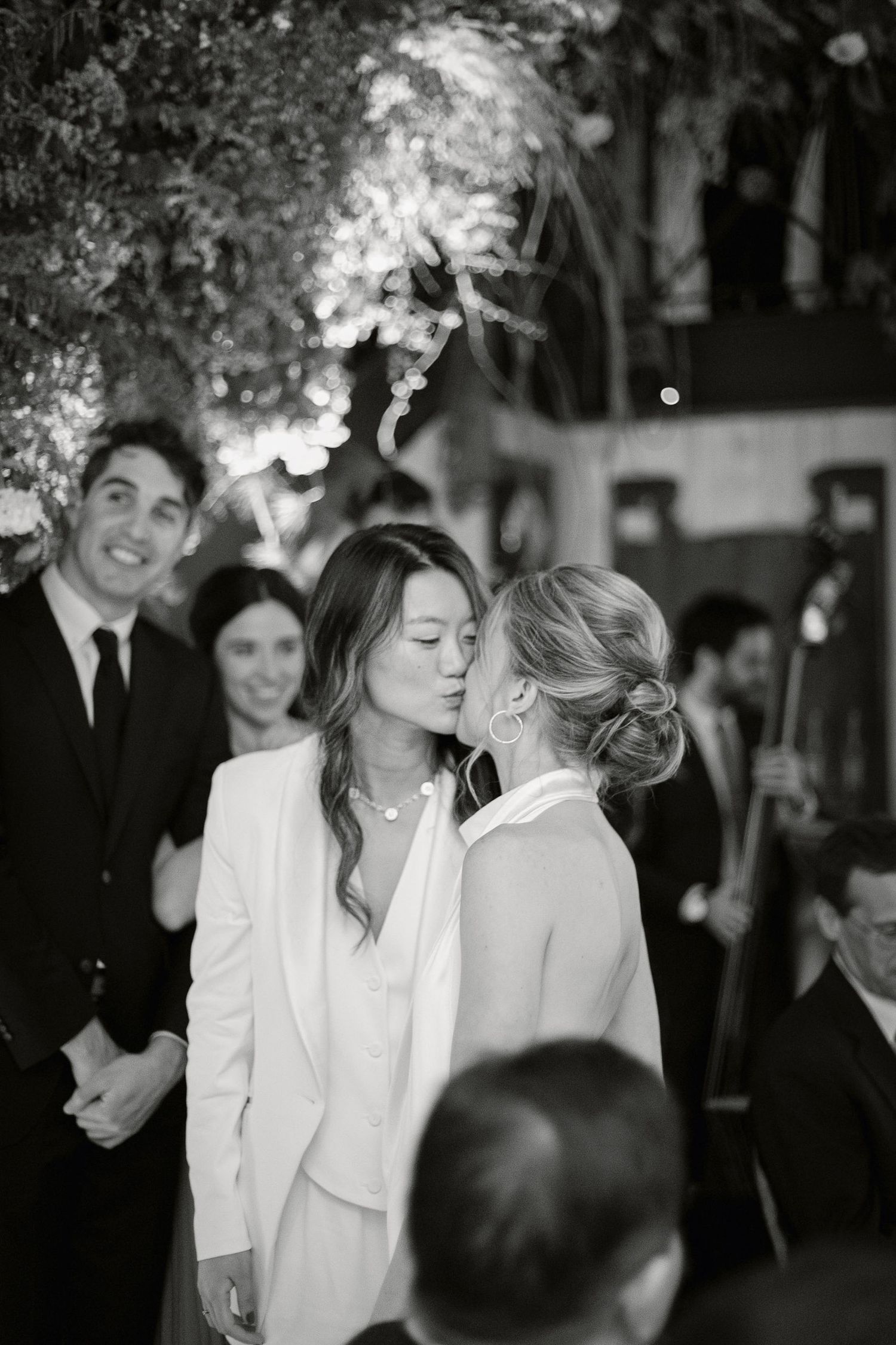 Monochrome wedding photos showing guests in formal attire sharing intimate moments during the celebration.