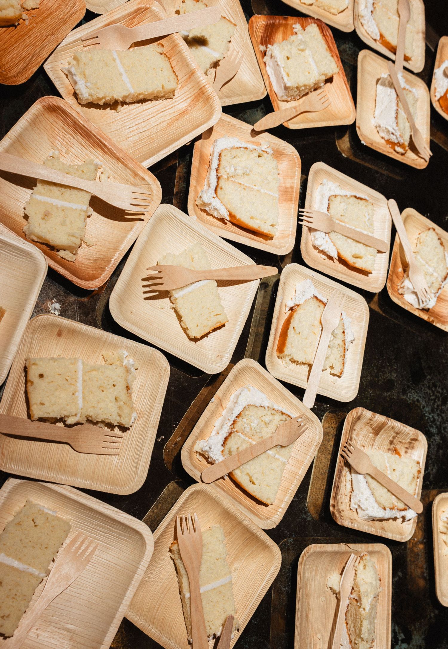 Overhead view of numerous disposable plates arranged on dark surface.