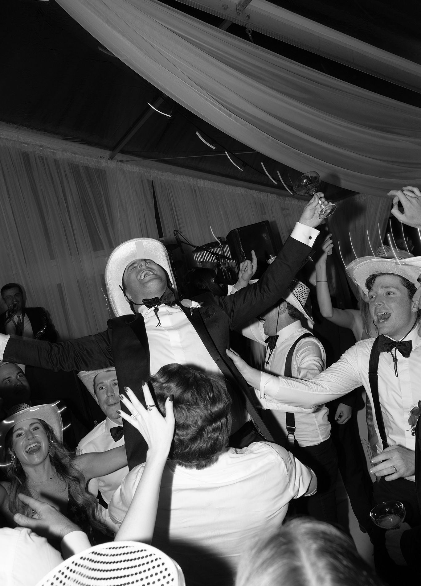 Crowd of people dancing and celebrating at a lively party with white tent ceiling.