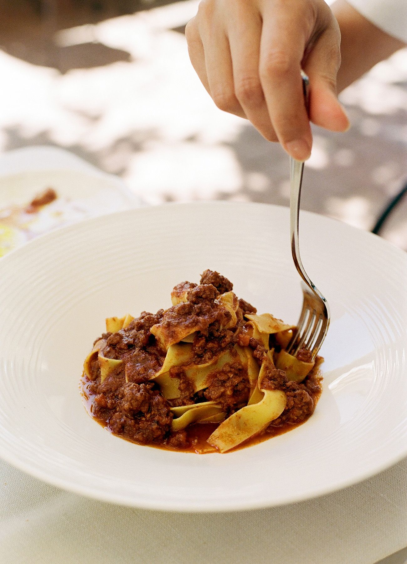 Plated pasta dish with meat sauce being served on white china.