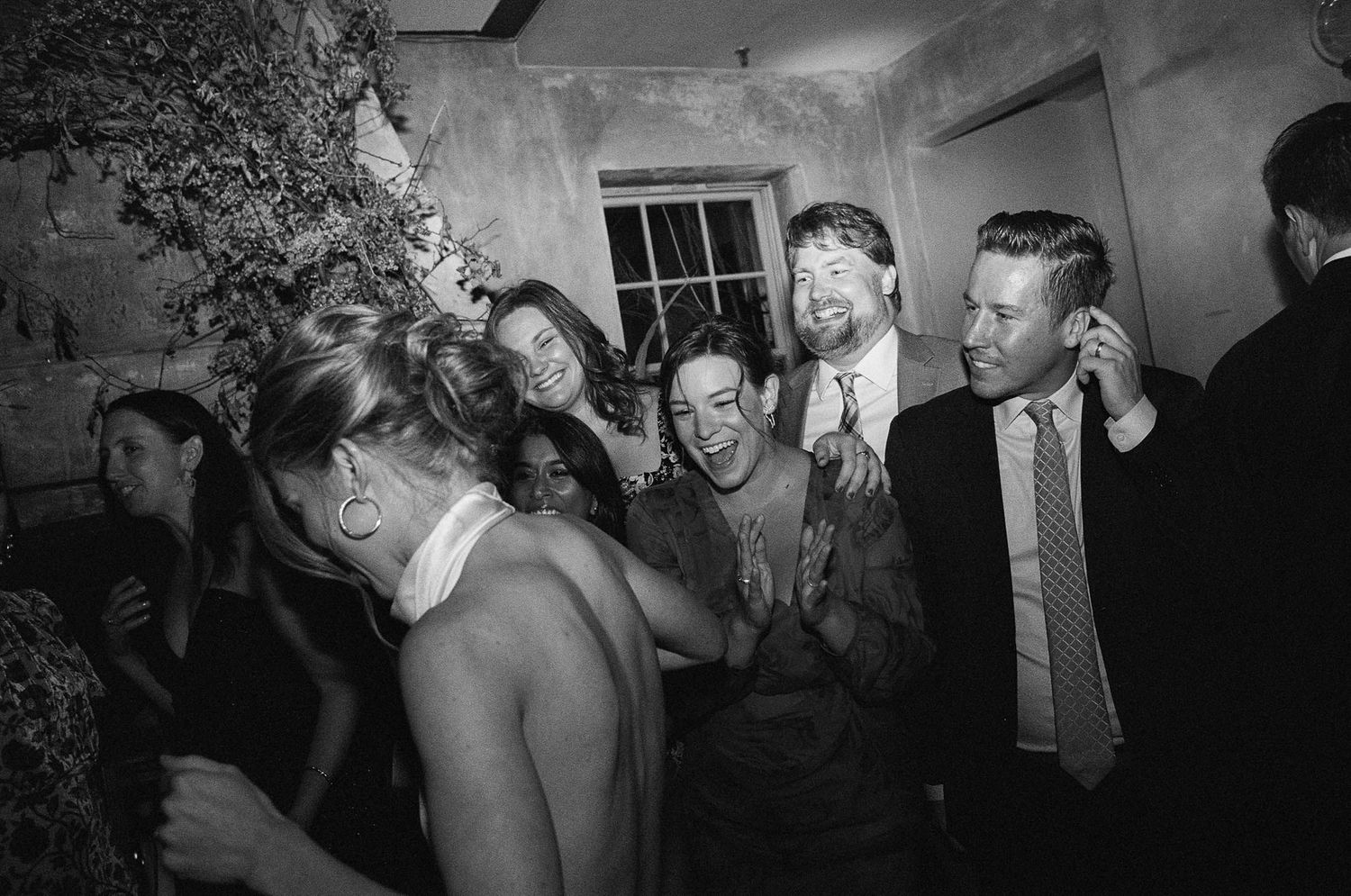 Wedding reception guests dancing and celebrating in a dimly lit venue.