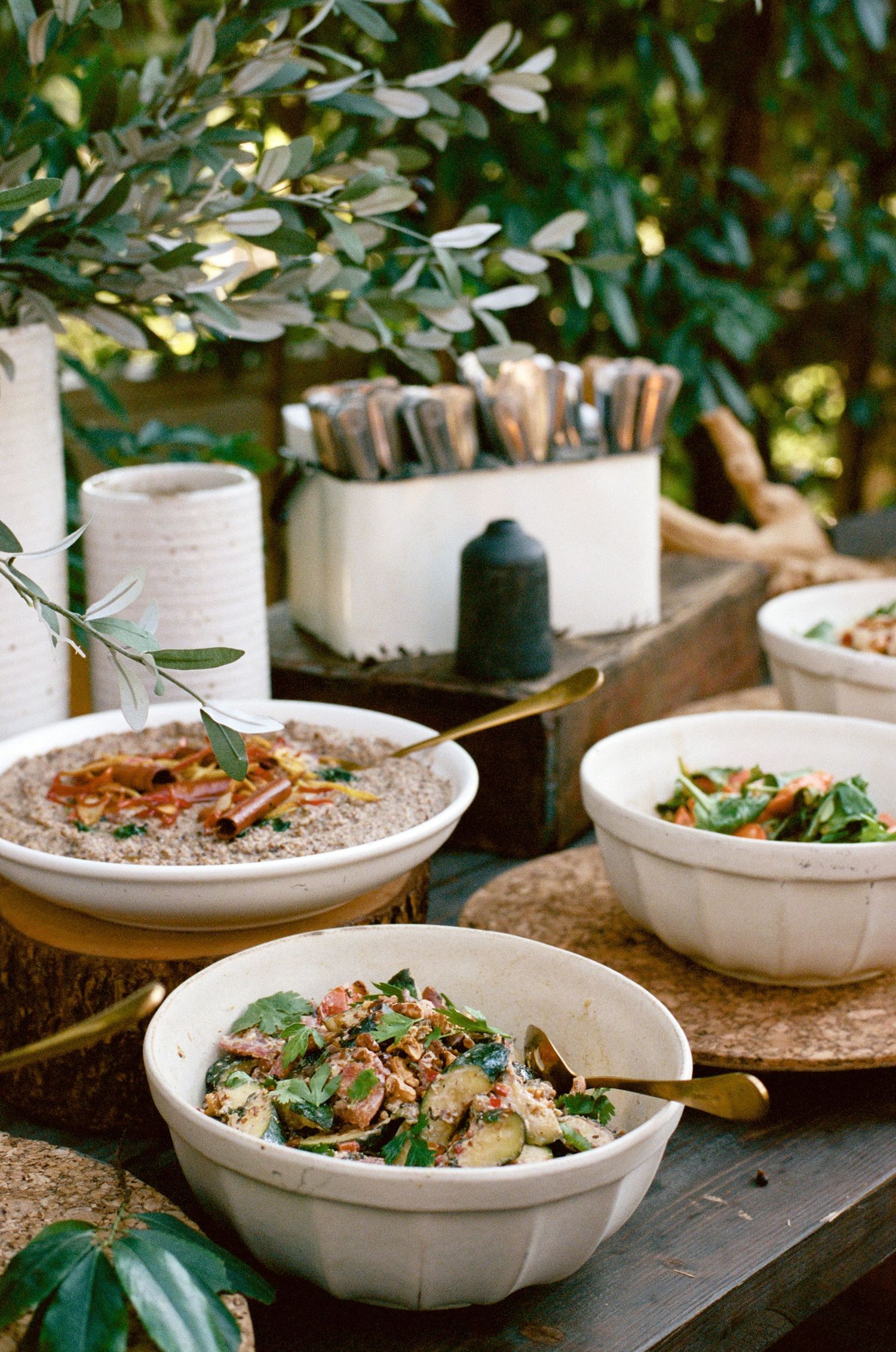 White ceramic bowls filled with creamy appetizers garnished with fresh herbs on a rustic wooden surface.
