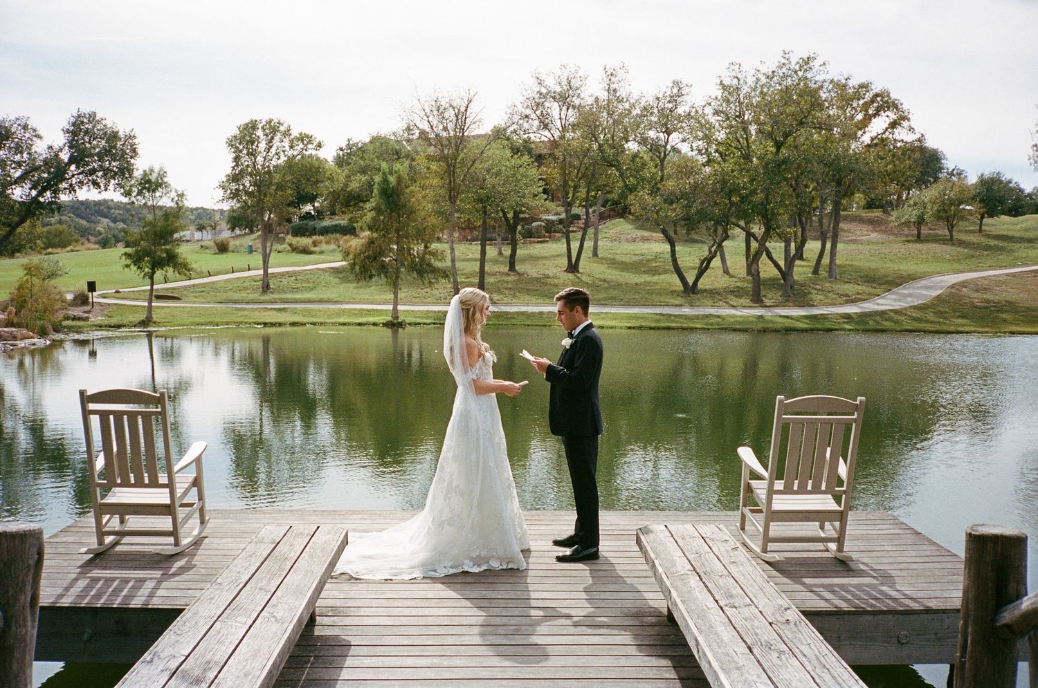 Wedding ceremony setup on a wooden dock overlooking a serene lake with chairs and floral arrangements.