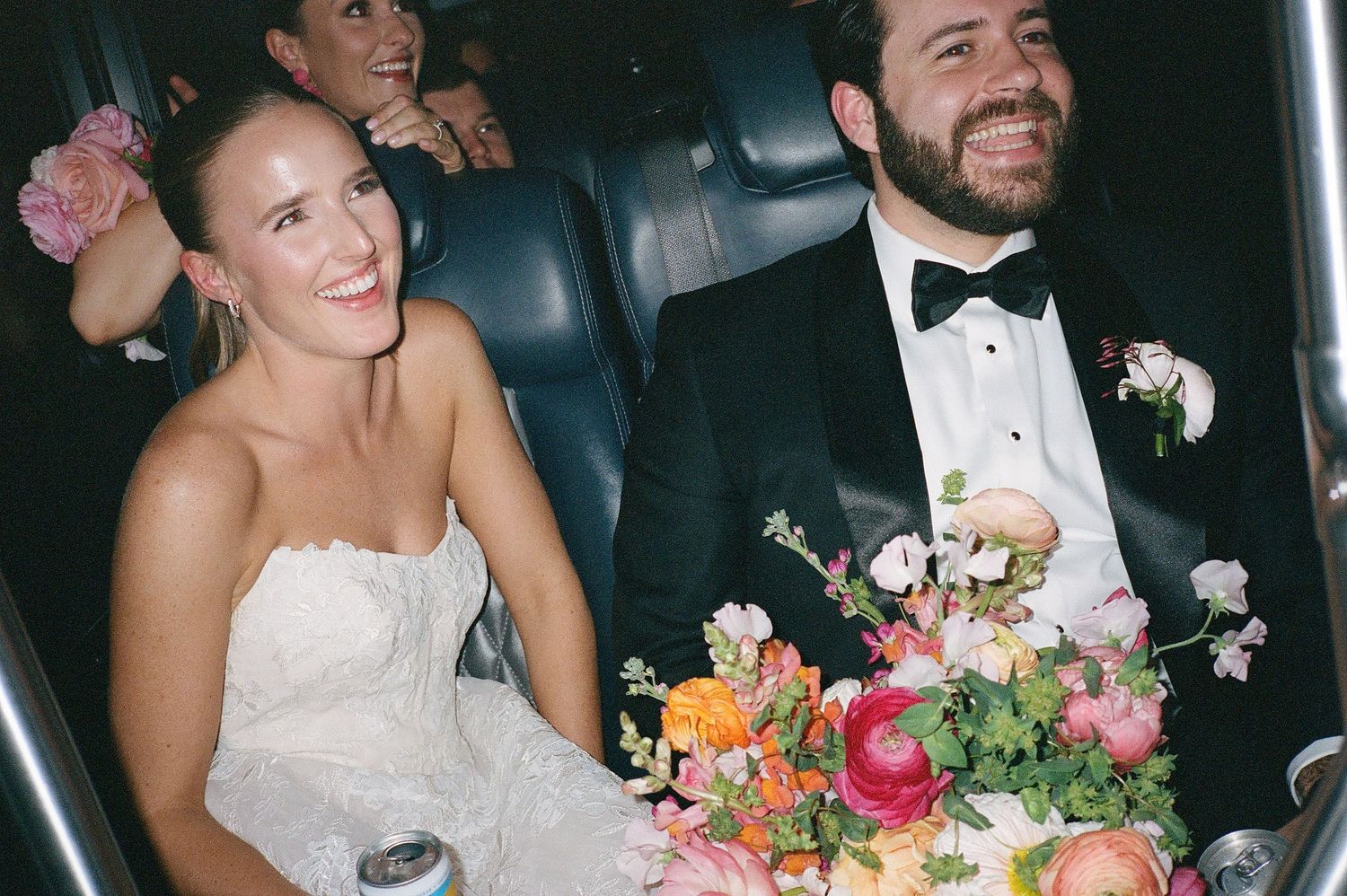 Wedding party celebrating in formal attire with bouquets and bow ties.