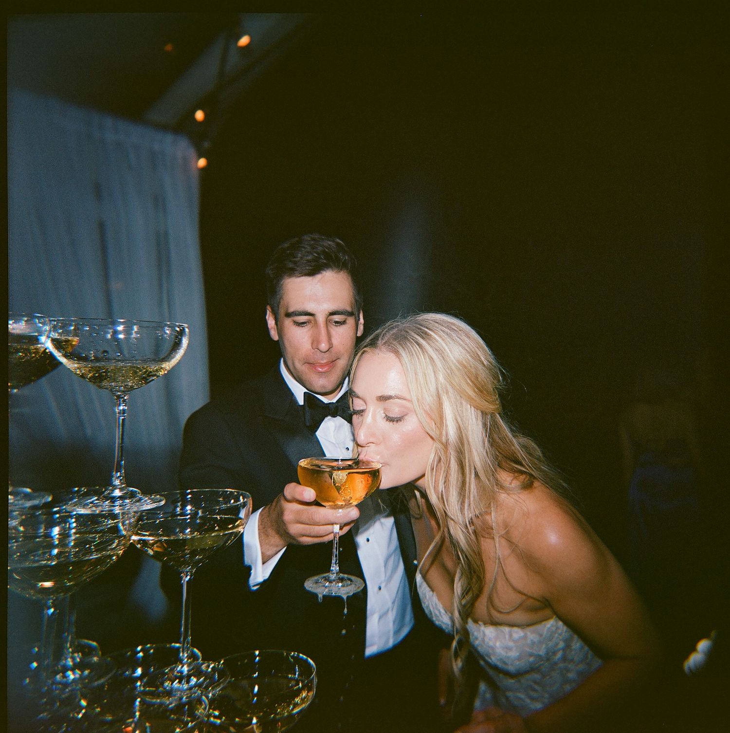 Wedding guests enjoying champagne and cocktails at an evening reception.