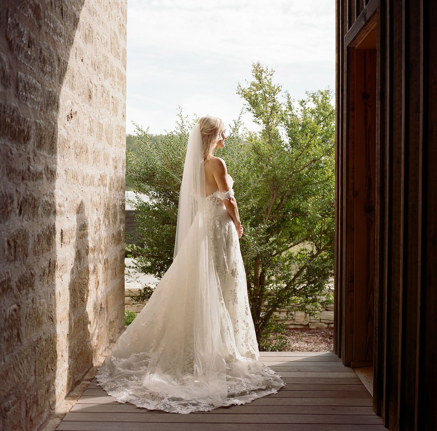 Elegant bridal gown with flowing train captured in a stone archway.