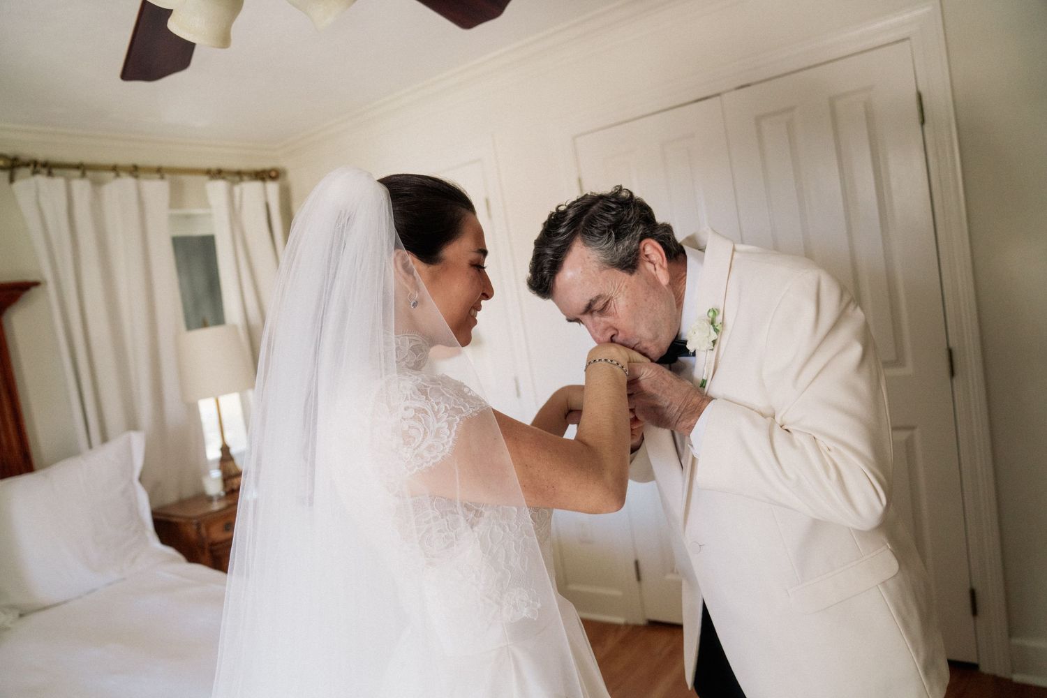 A tender moment between newlyweds in a sunlit room with white decor.