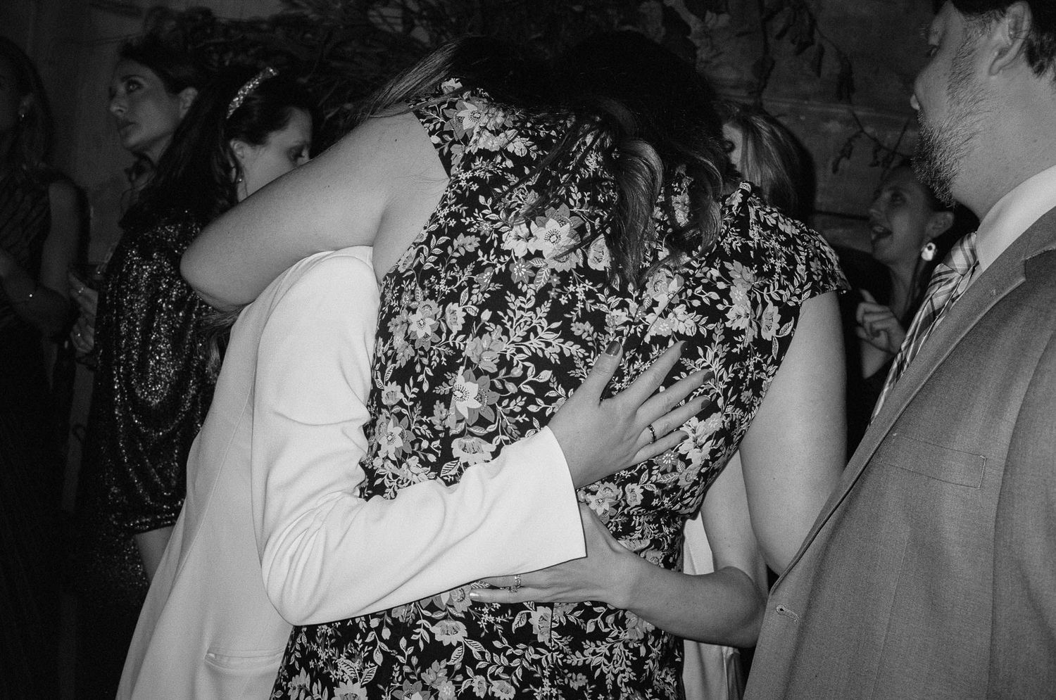 Black and white photo of wedding guests dancing and celebrating at a lively reception party.