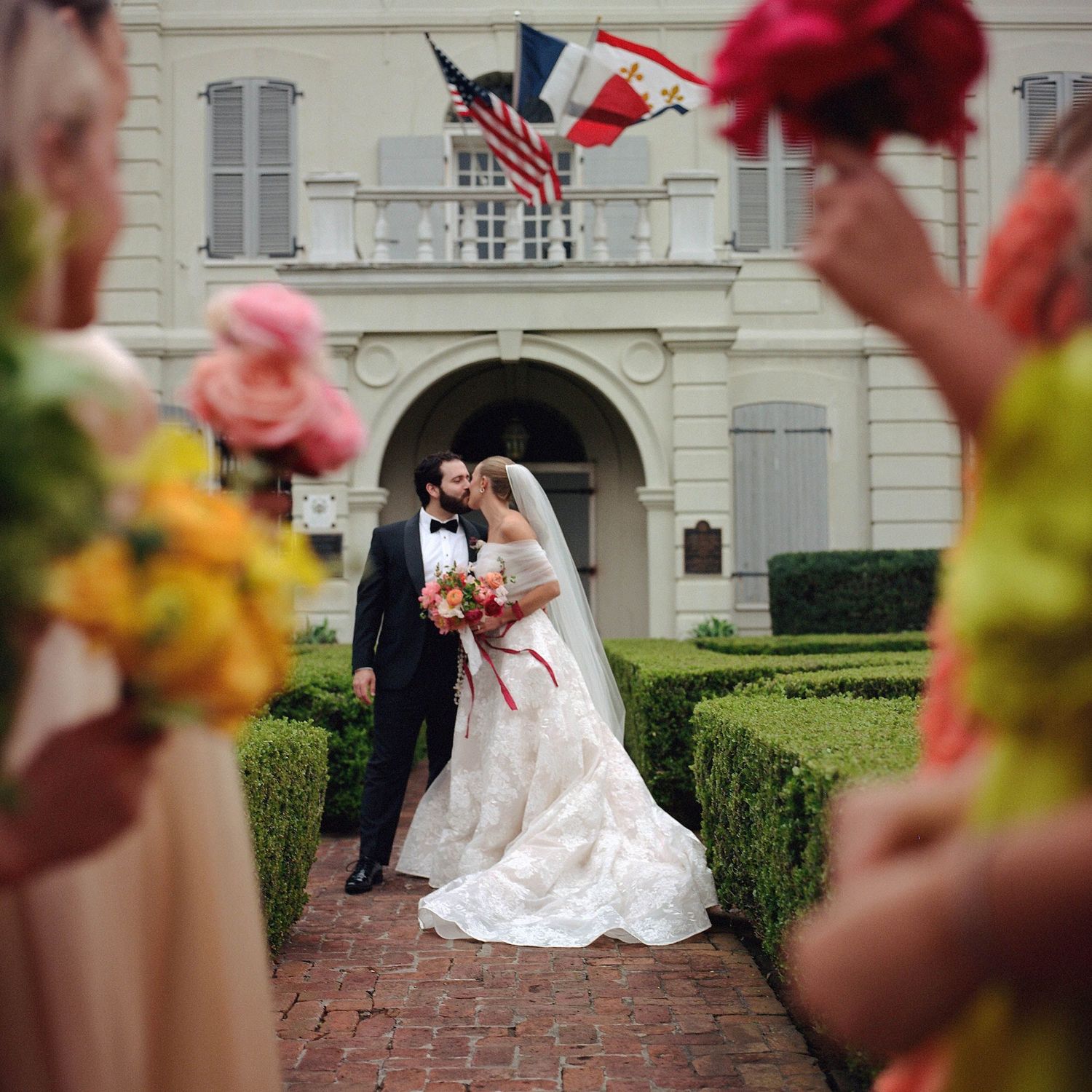 Wedding couple posing on brick steps in front of an elegant white building.