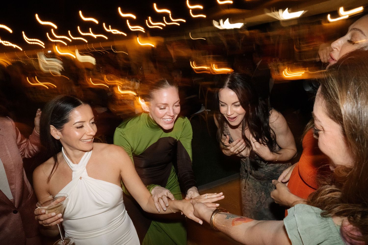 Lively dance party scene with people moving under warm ambient lighting.