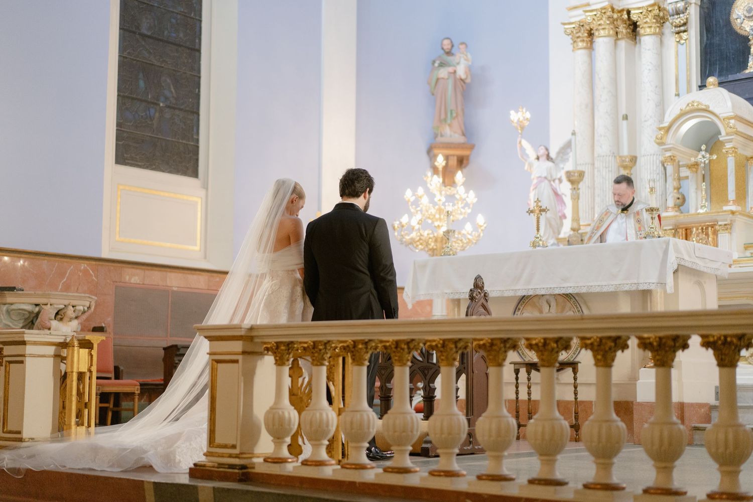 Interior of an elegant church with ornate architecture and chandeliers during a wedding ceremony.