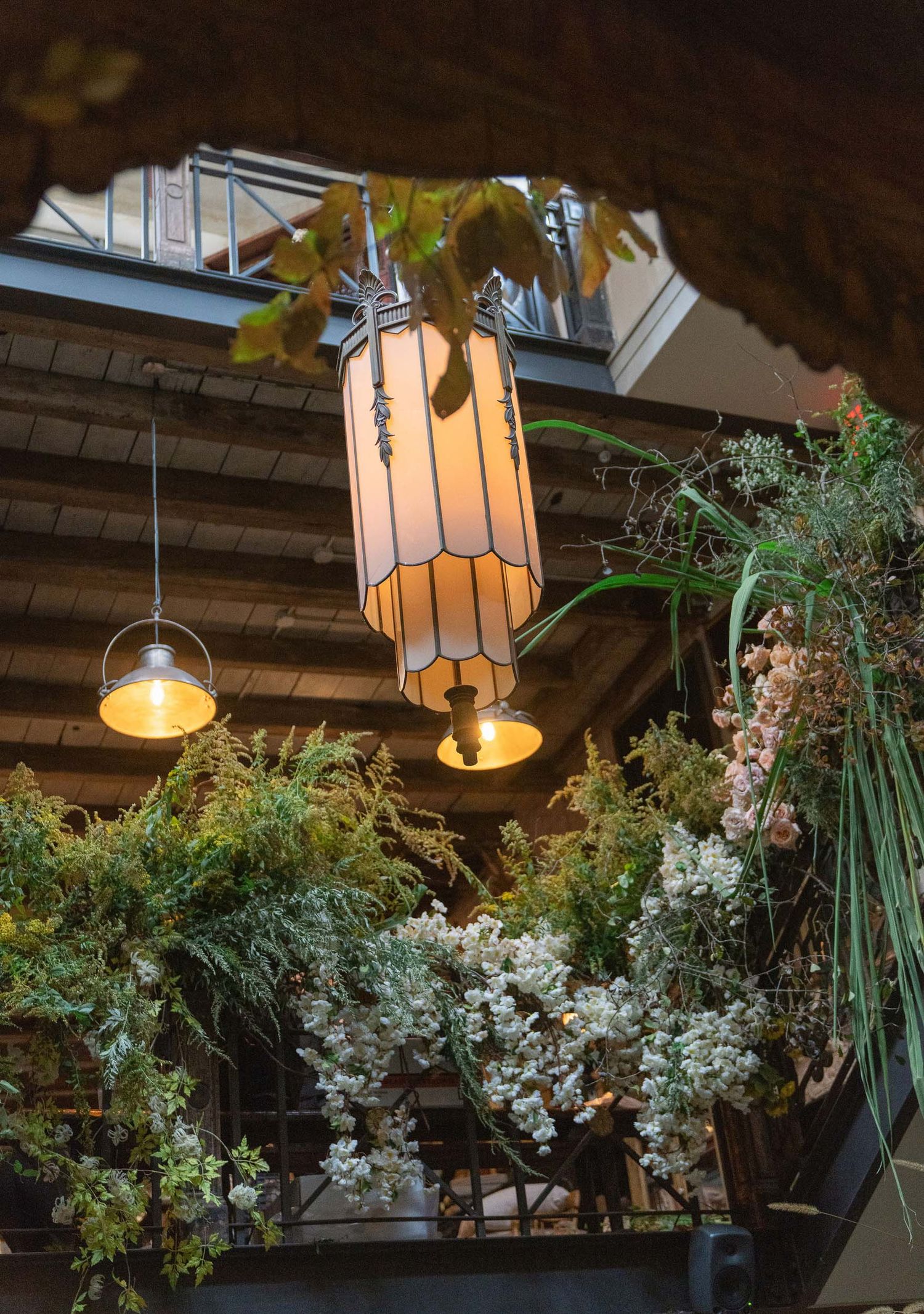 Hanging floral arrangements with white blooms and greenery suspended from wooden beams create an elegant ceiling display.