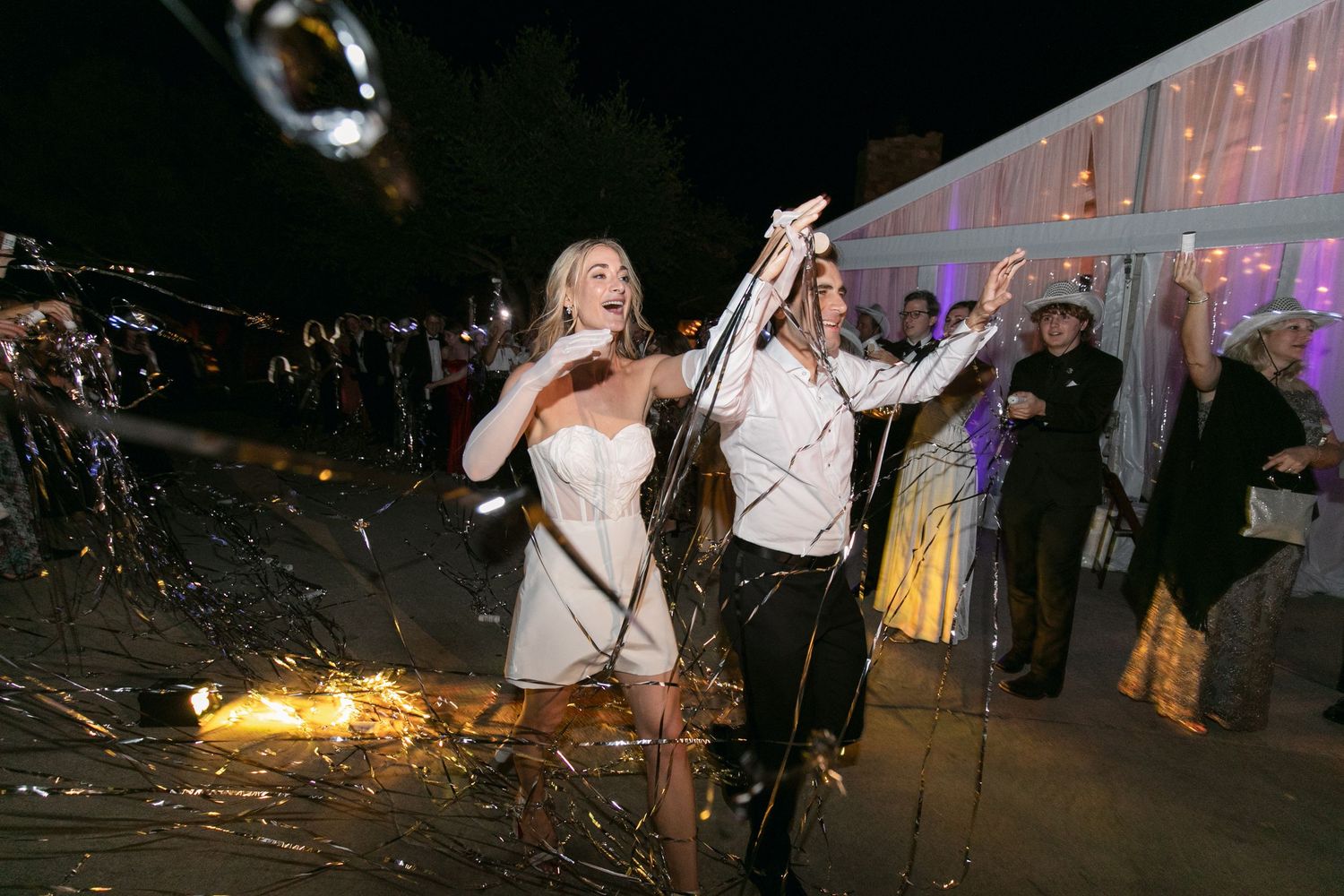 Evening wedding celebration with sparklers creating trails of light against the dark sky.