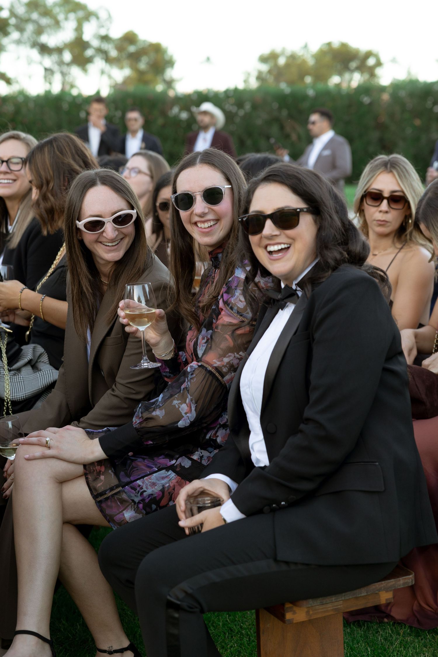 Wedding guests enjoying drinks and conversation while seated outdoors during a celebration.